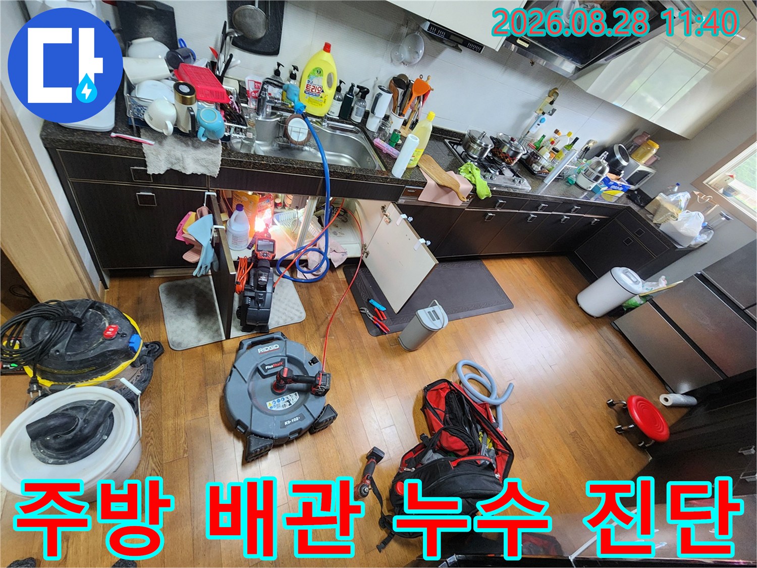 싱크대 아래 배관 주위에 배치된 장비와 점검 중인 현장 모습입니다.
