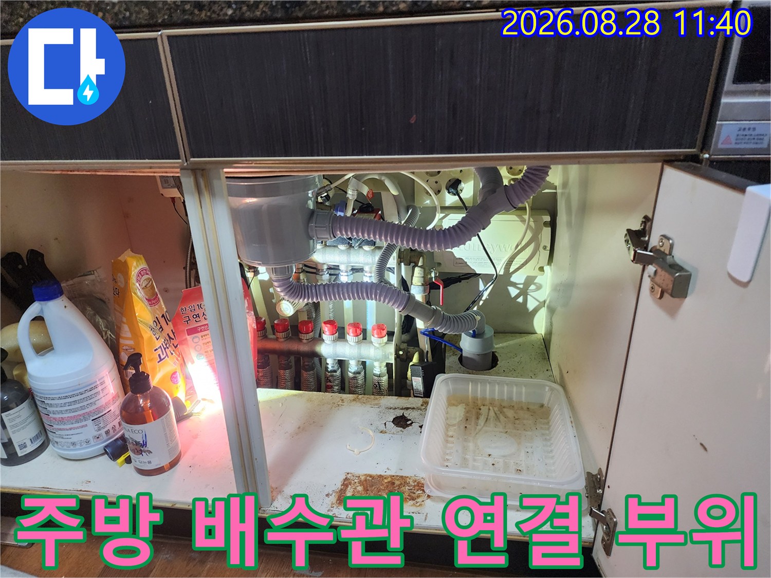 싱크대 하부장에 설치된 여러 개의 배관과 호스들의 연결 상태를 보여줍니다.
