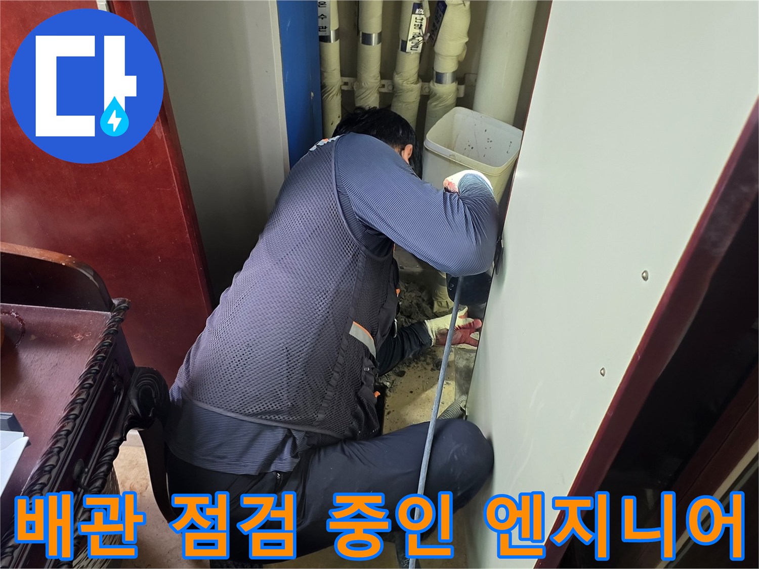 배관 점검을 위해 작업자가 좁은 공간에서 장비를 확인하는 모습