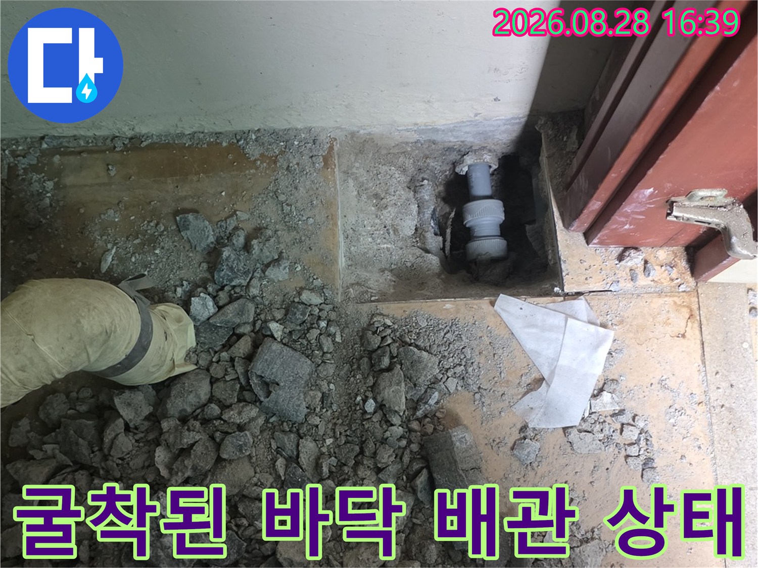 콘크리트 파쇄 후 노출된 수도 배관과 흩어진 잔해물 사진입니다.
