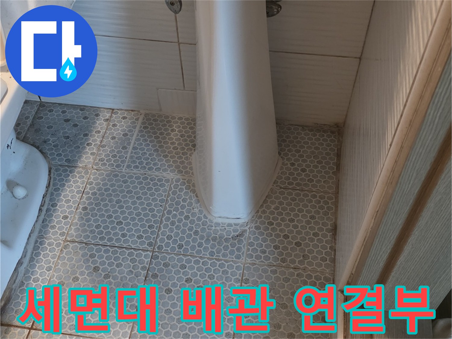 하얀색 세면대 하단 수전과 바닥 타일이 만나는 구간
