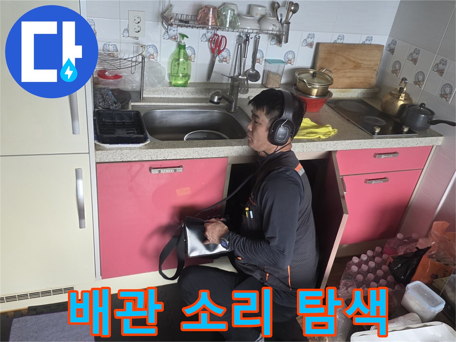 헤드셋 형태의-청음기를 착용한 엔지니어가-싱크대 하부를 점검함