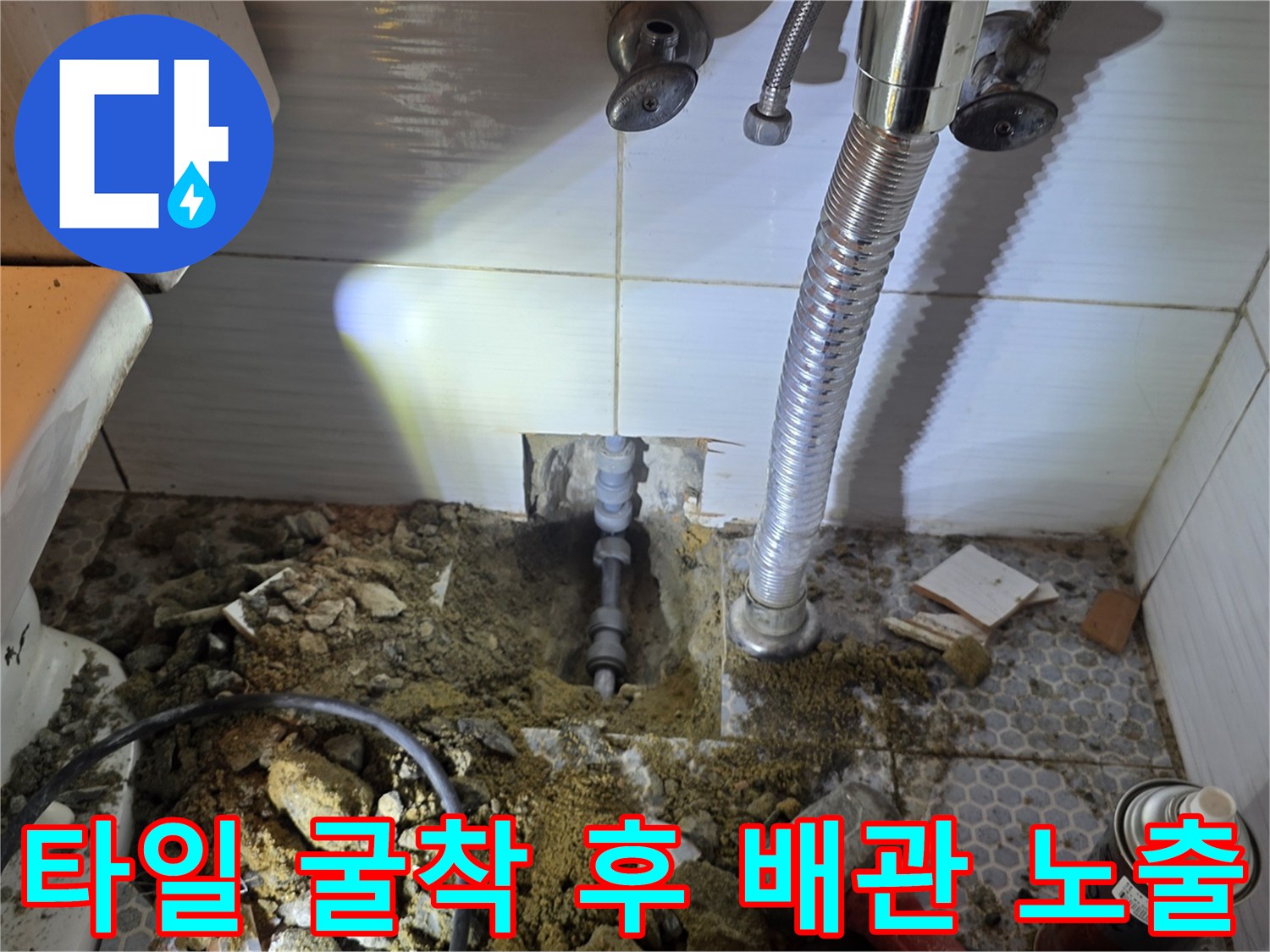 화장실 세면대 하부 굴착을 통해 드러난 노출된 배관과 주변 파편들