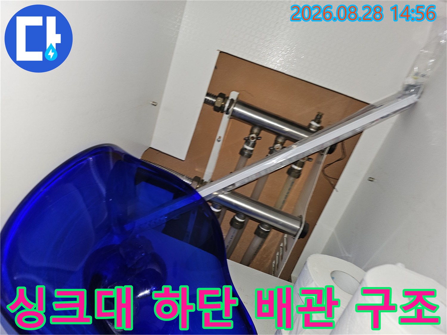 싱크대 아래쪽 공간에 설치된 다양한 크기의 배관들과 연결 부품들입니다.