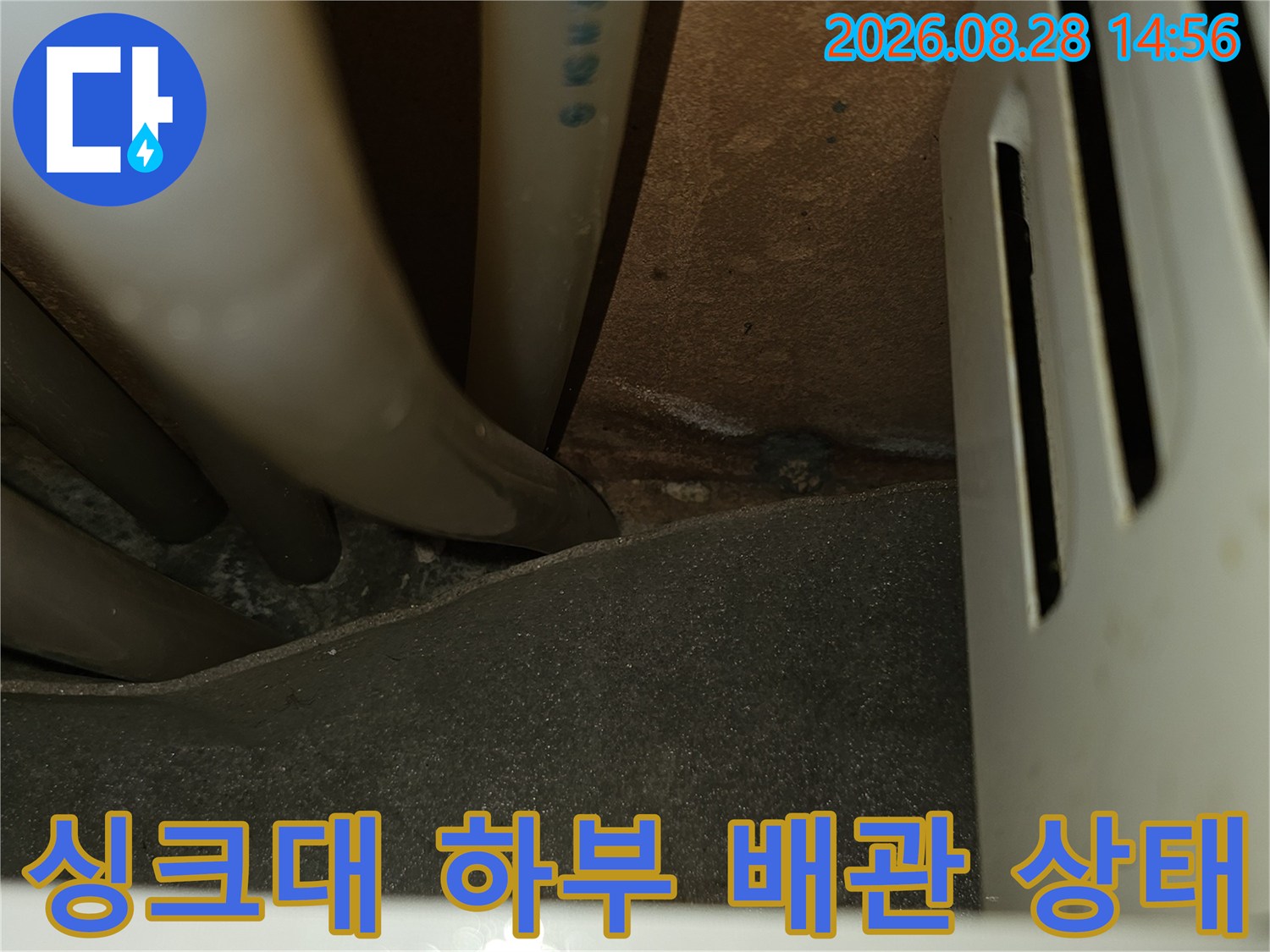어두운 싱크대 아래 공간의 배관 굴곡 및 연결 부위 상세 사진