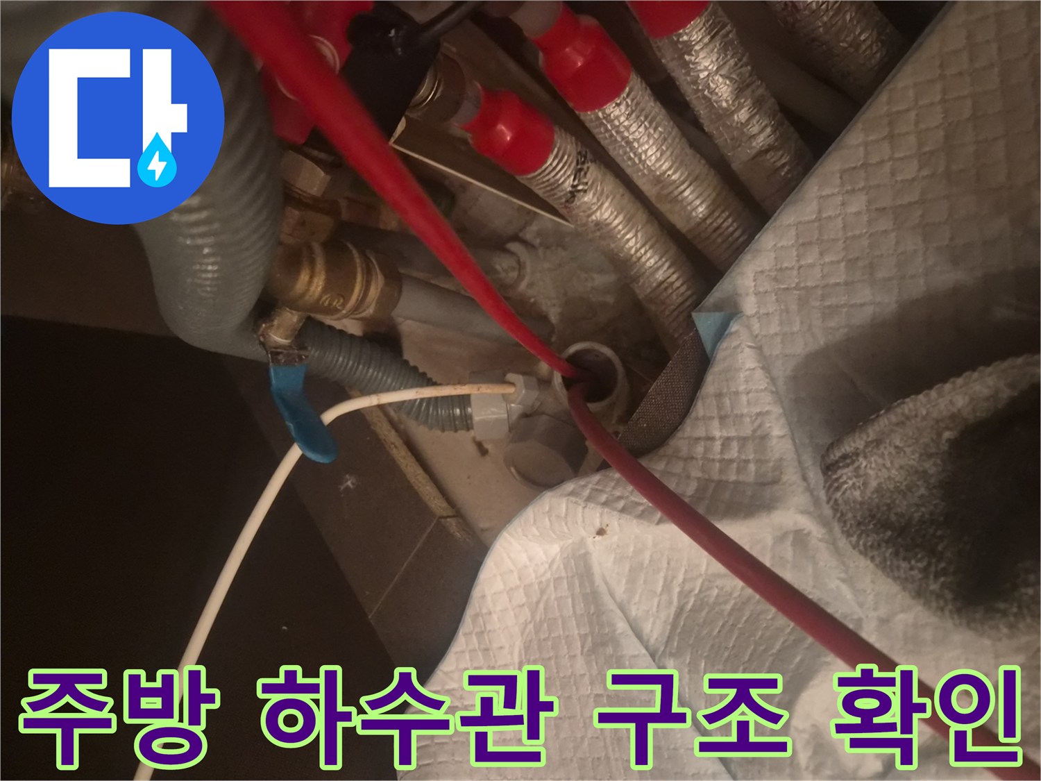 은색 보온재로 감싸진 배관들과 붉은색 호스가 교차하는 하수구 작업 부위