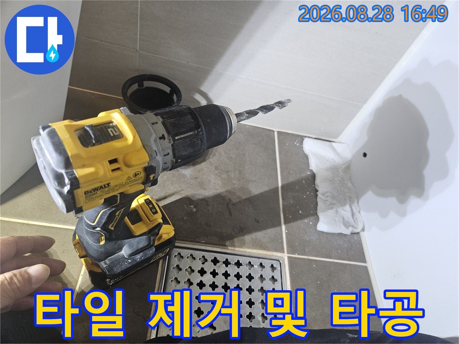 벽면 타일을 드릴로 타공하여 배관을 확인하는 장면입니다.