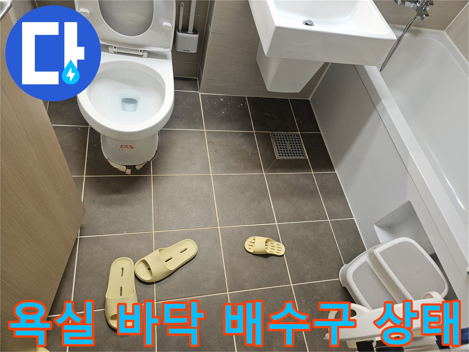 화장실 타일 벽면에 위치한 배수구와 변기 모습입니다.