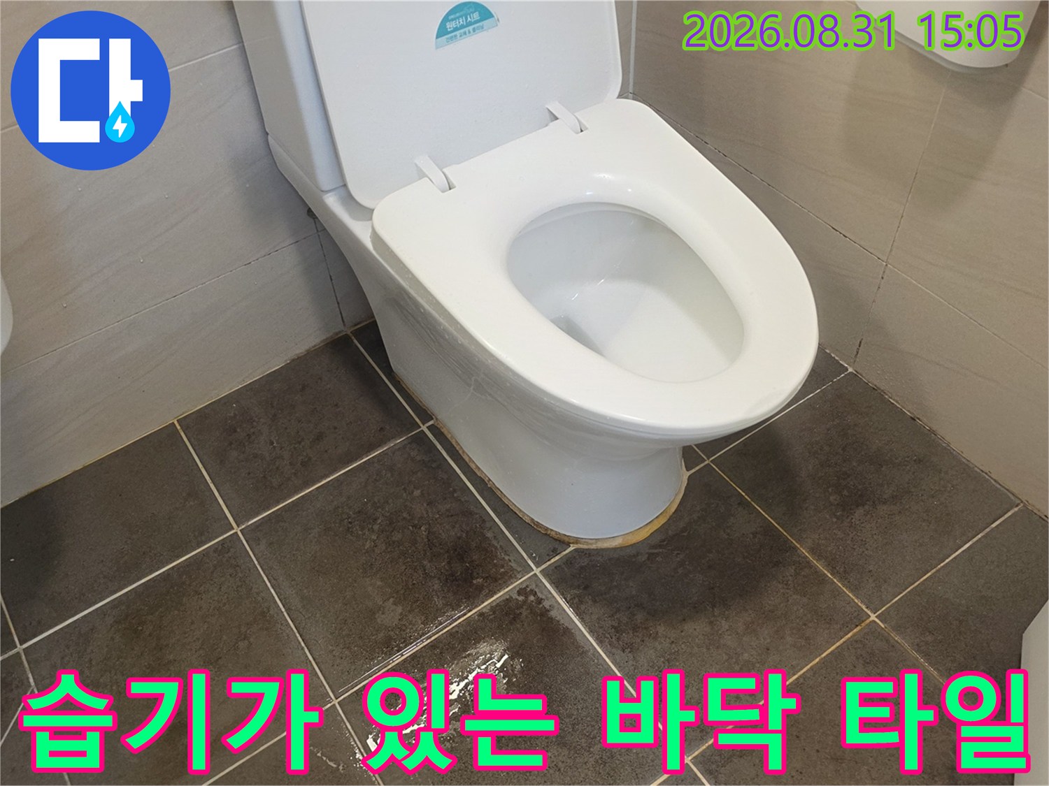 물기로 인해 젖어 보이는 화장실 바닥과 양변기 사진입니다.