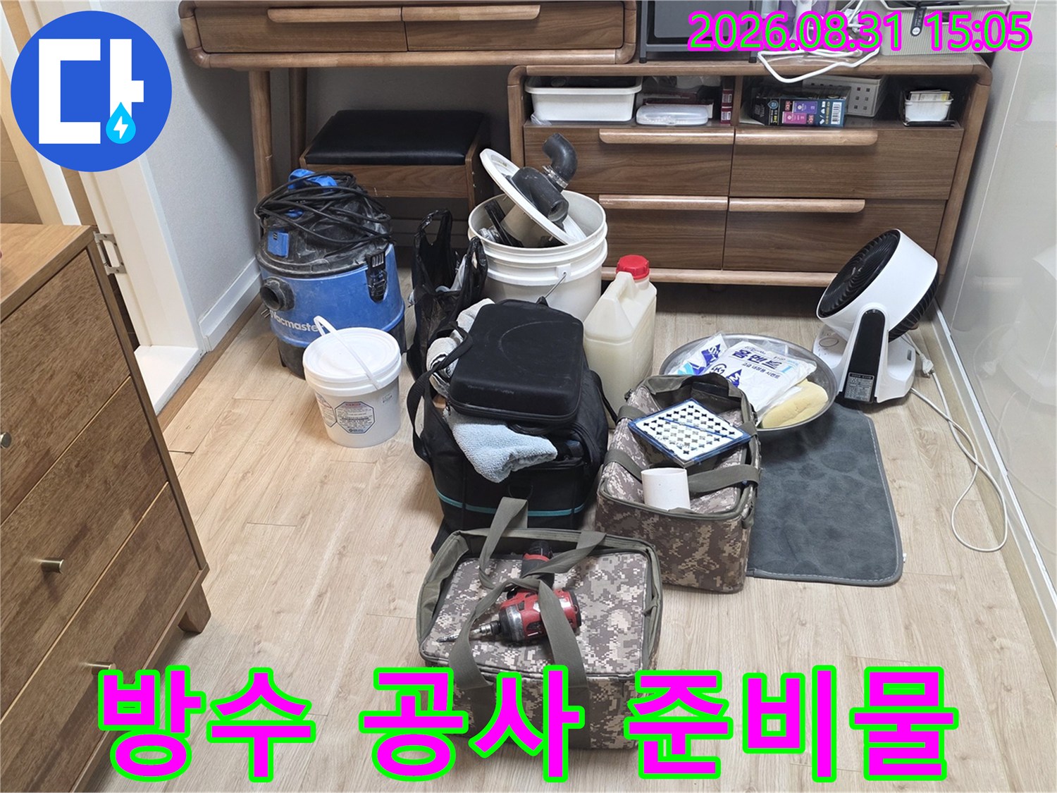 화장실 방수층 보강 작업을 위해 거실 바닥에 나열된 작업용 가방과 도구들