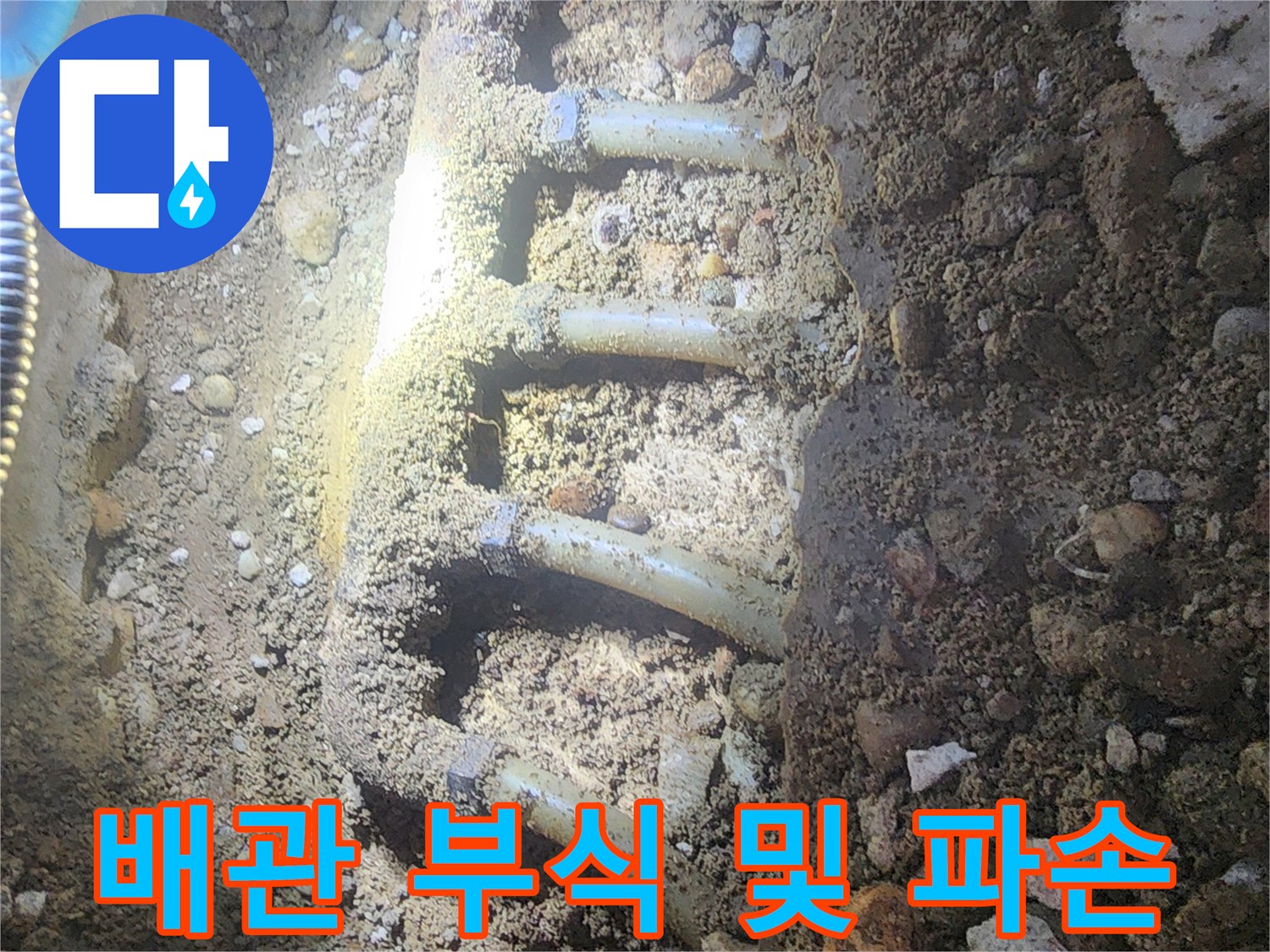 자갈 층 아래 드러난 파손된 배관 연결부