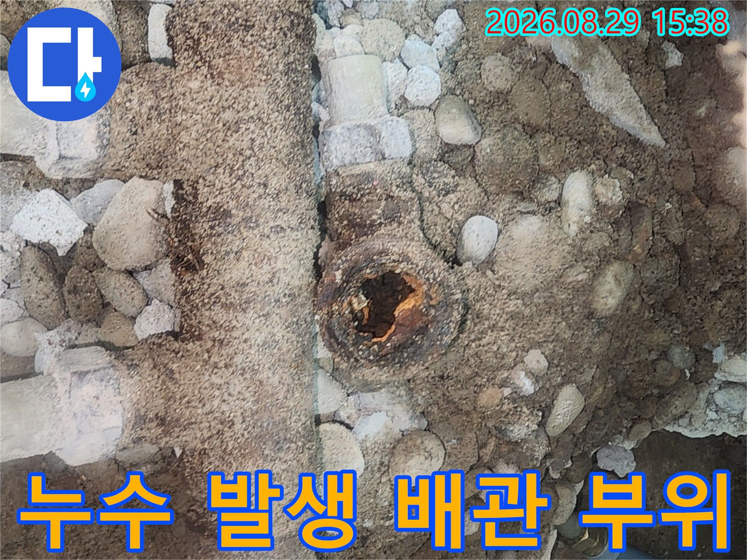 흙과 자갈 사이로 보이는-부식된 수도 분배기 연결부