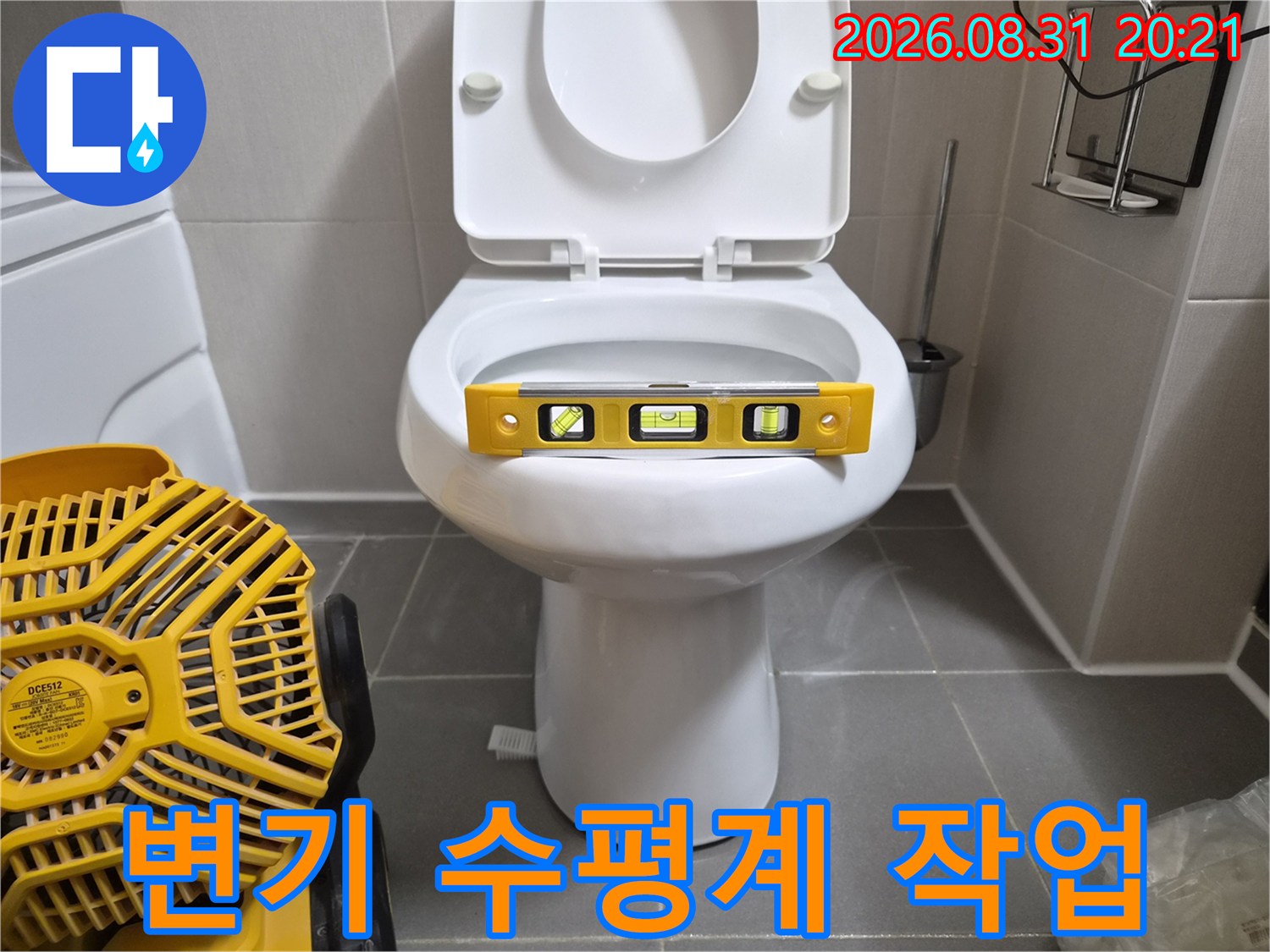 변기 도기 위에 놓인 노란색 수평계와 작업용 송풍기