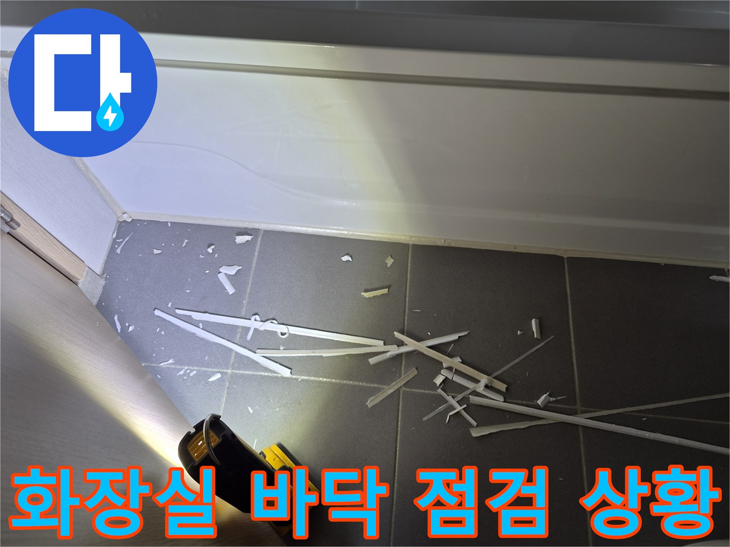 손전등으로 비춘-화장실 타일 바닥의 파편과 상태