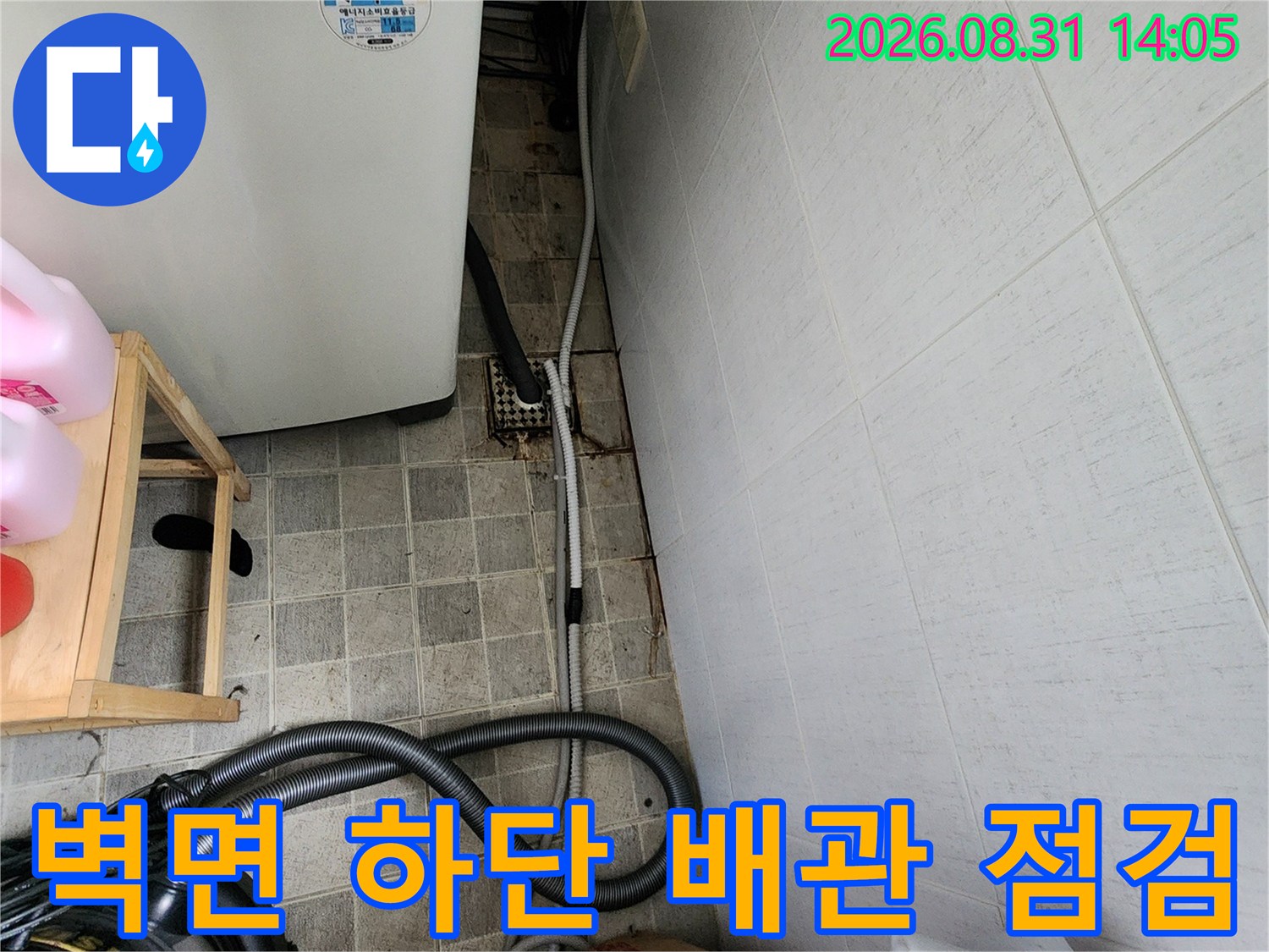 타일 벽면 하단의 노출된 배관과 주변 환경을 정밀하게 조사하는 과정입니다.