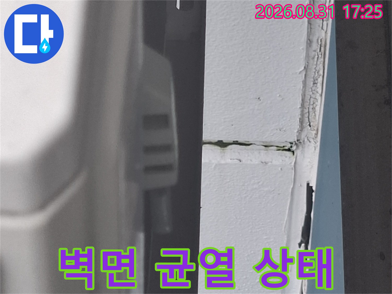 하얀 외벽 면에 나타난 수직 방향의 크랙과 배관 부위입니다.