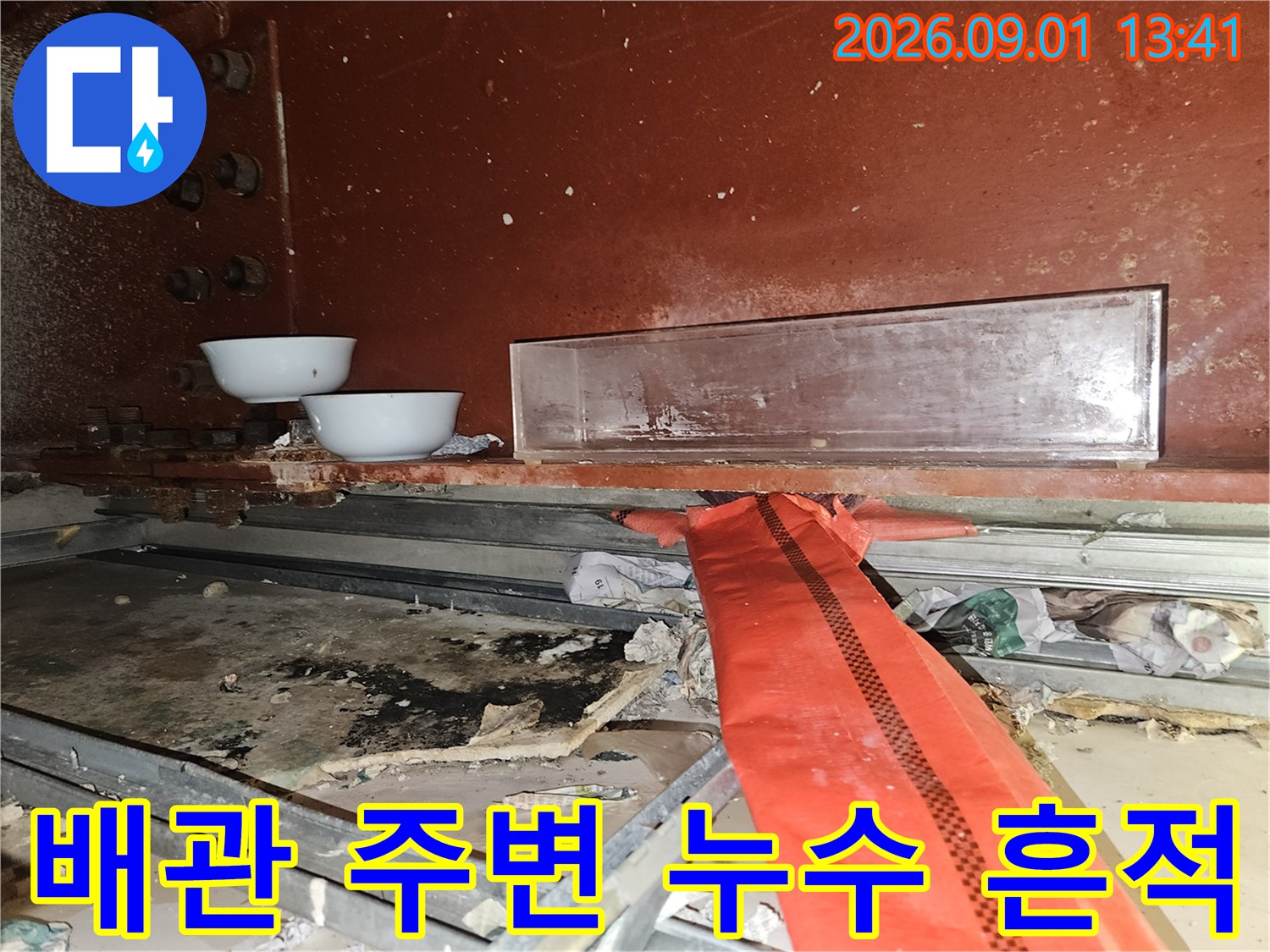 붉은색 배관과 상단 도기 사이의 오염된 바닥면을 촬영했습니다.