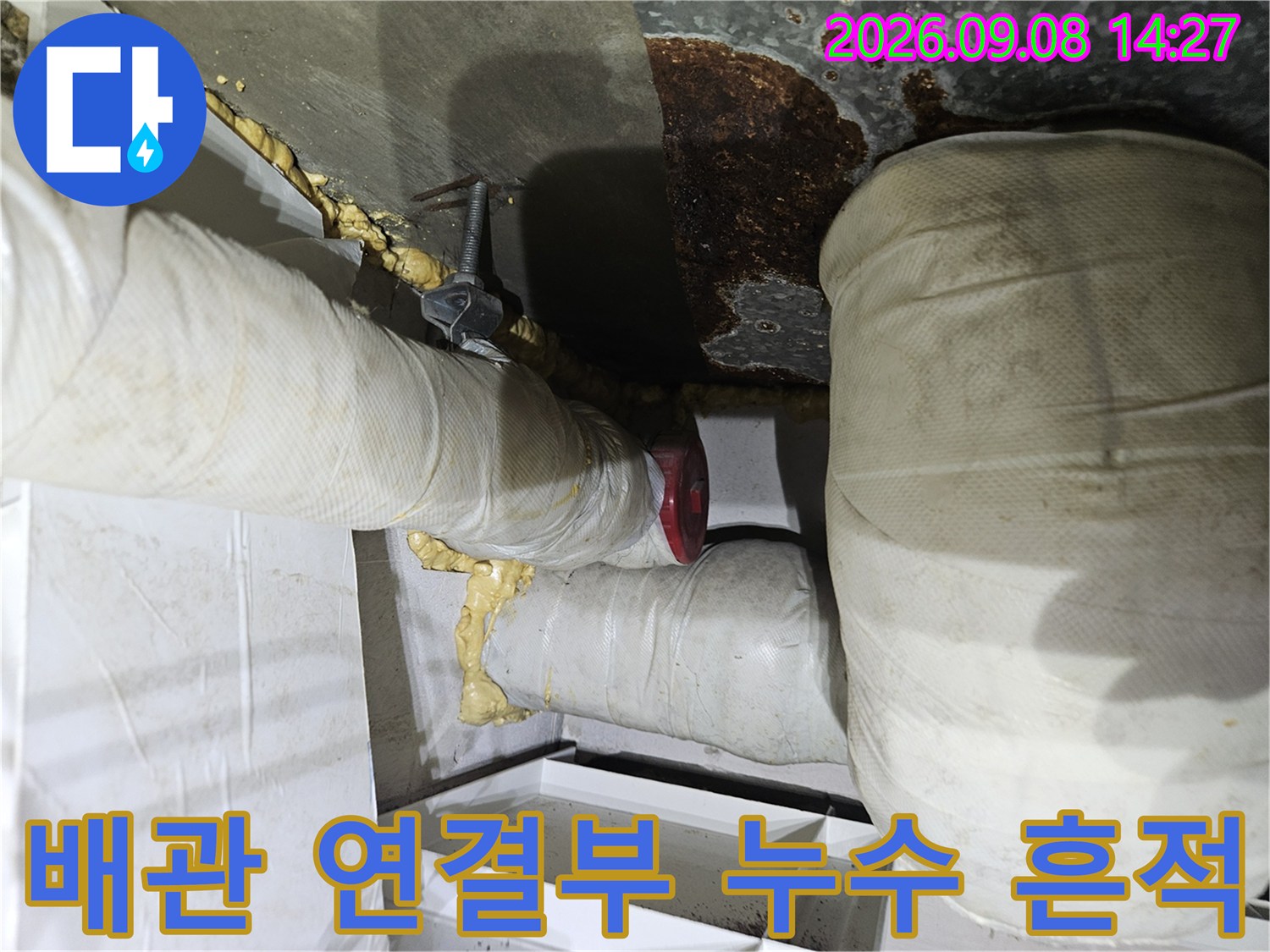 단열재로 덮인 배관-연결 부위의 부식과 오염된 슬라브 면을 보여줍니다.