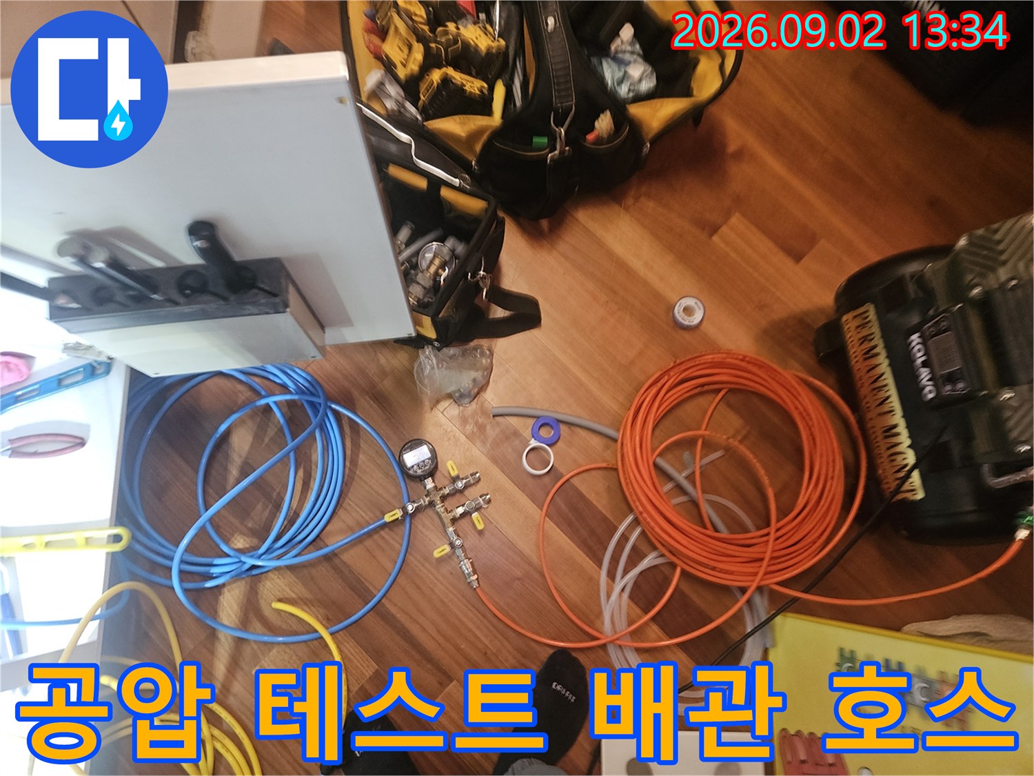 누수 탐지를 위해 바닥에 펼쳐진 압력 측정용 호스와 작업 도구들입니다.