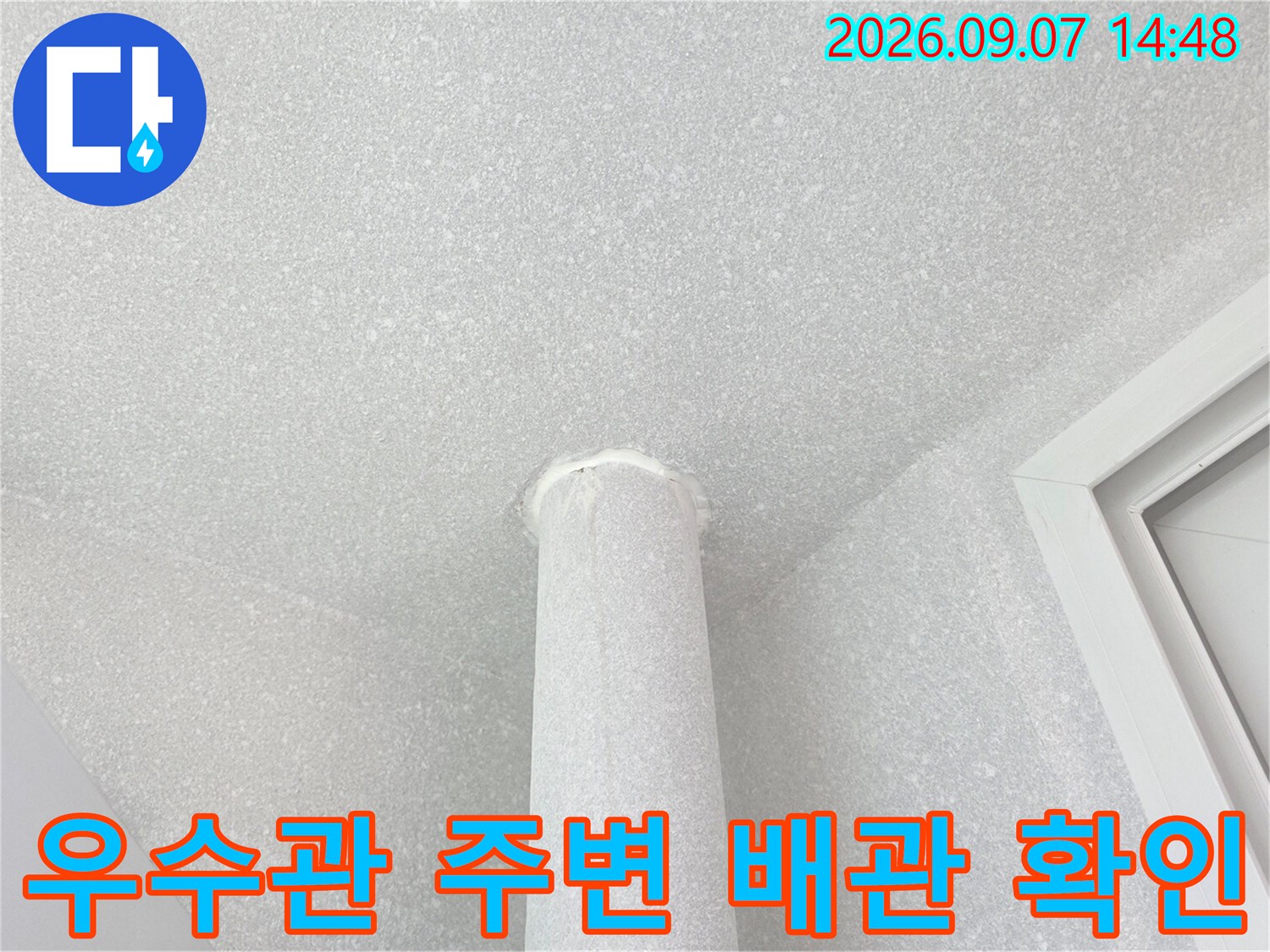 천장 마감재와 연결된 흰색 우수관 배관의 근접 사진입니다.