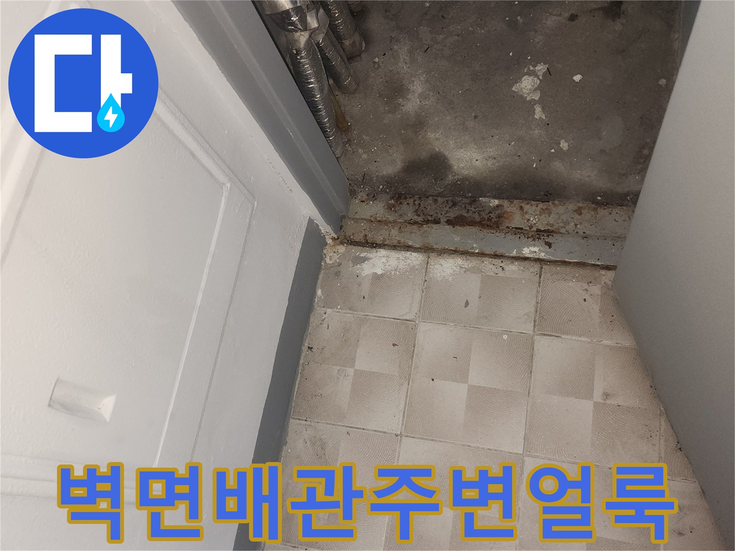 배관 주변의 젖은 벽면과 변색된 타일 경계 부위