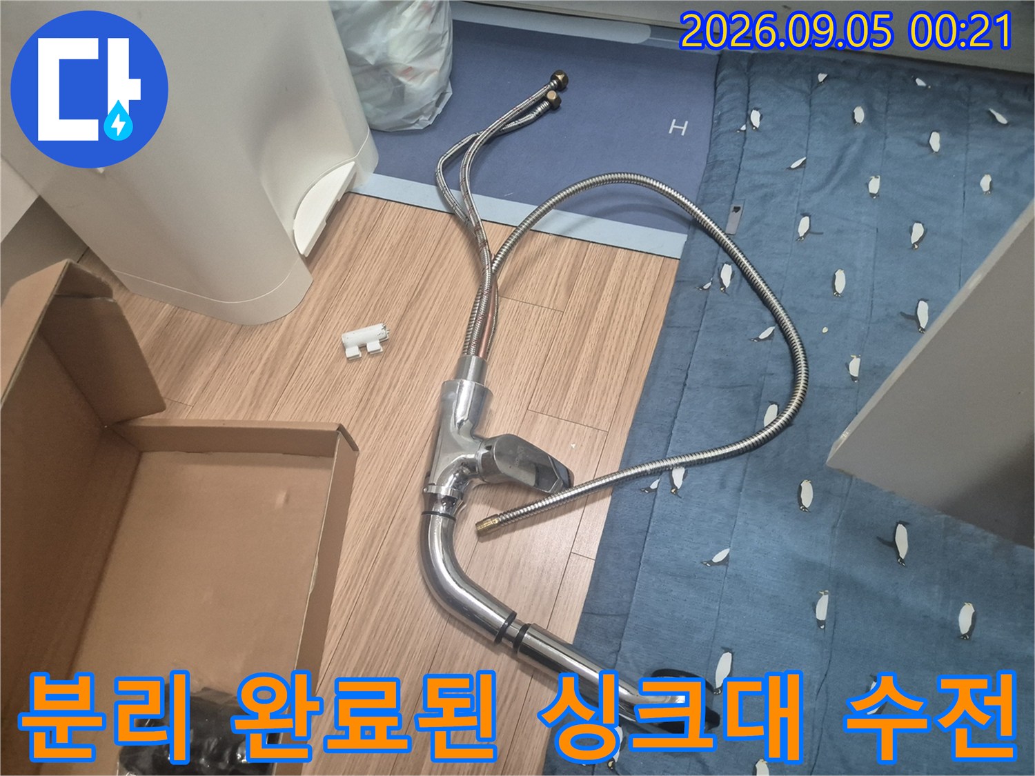 바닥에 놓인 탈거된 싱크대 수전과 굴곡진 호스 부위