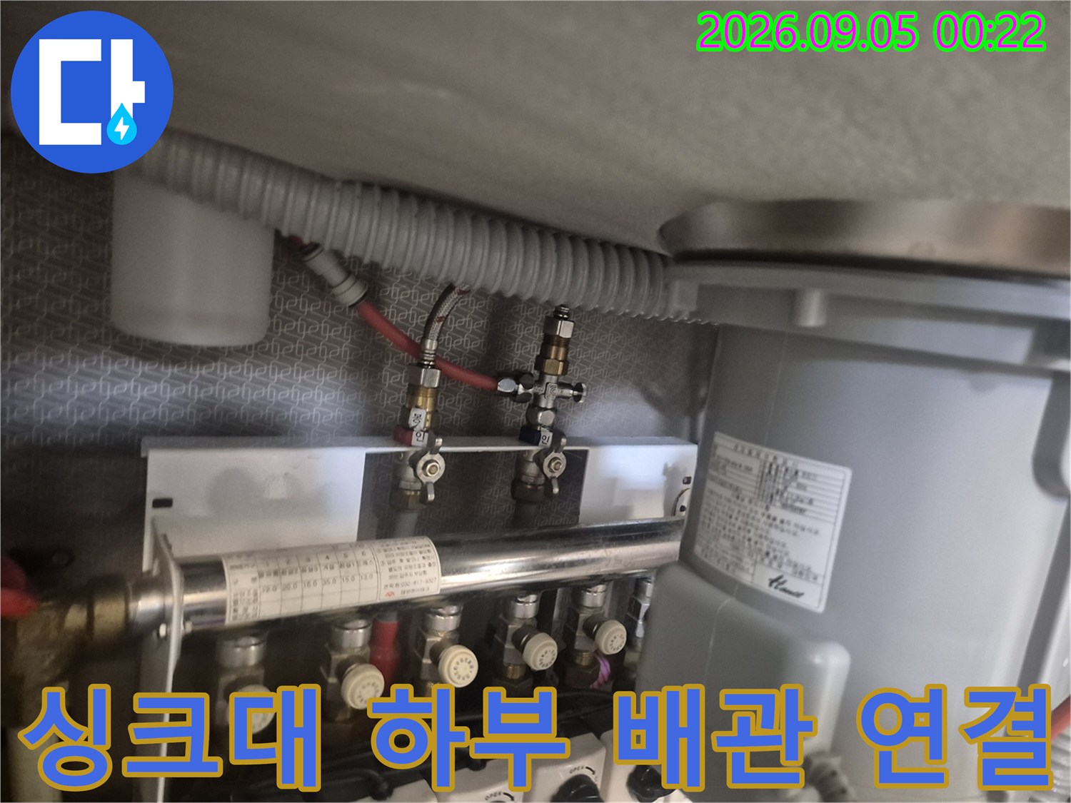 싱크대 하부장의 수전 급수 밸브와 호스 연결 상태를 점검하는 장면입니다.