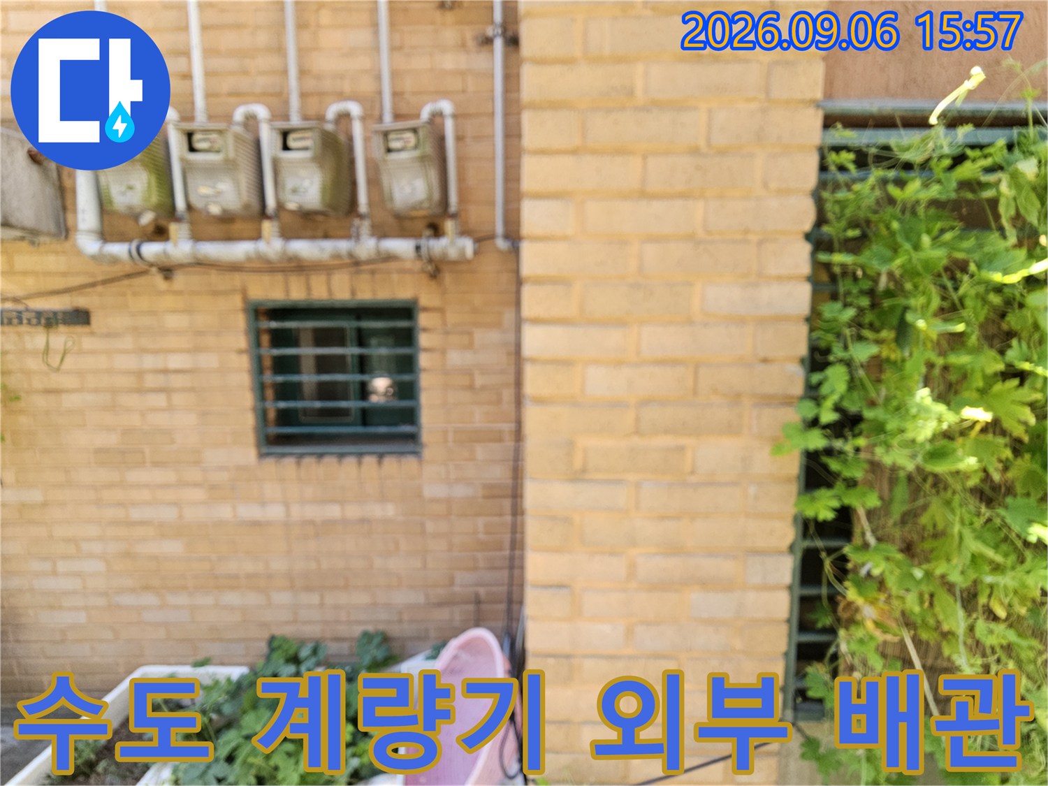 벽돌 외벽에 설치된 수도 계량기와 연결된 급수 관로
