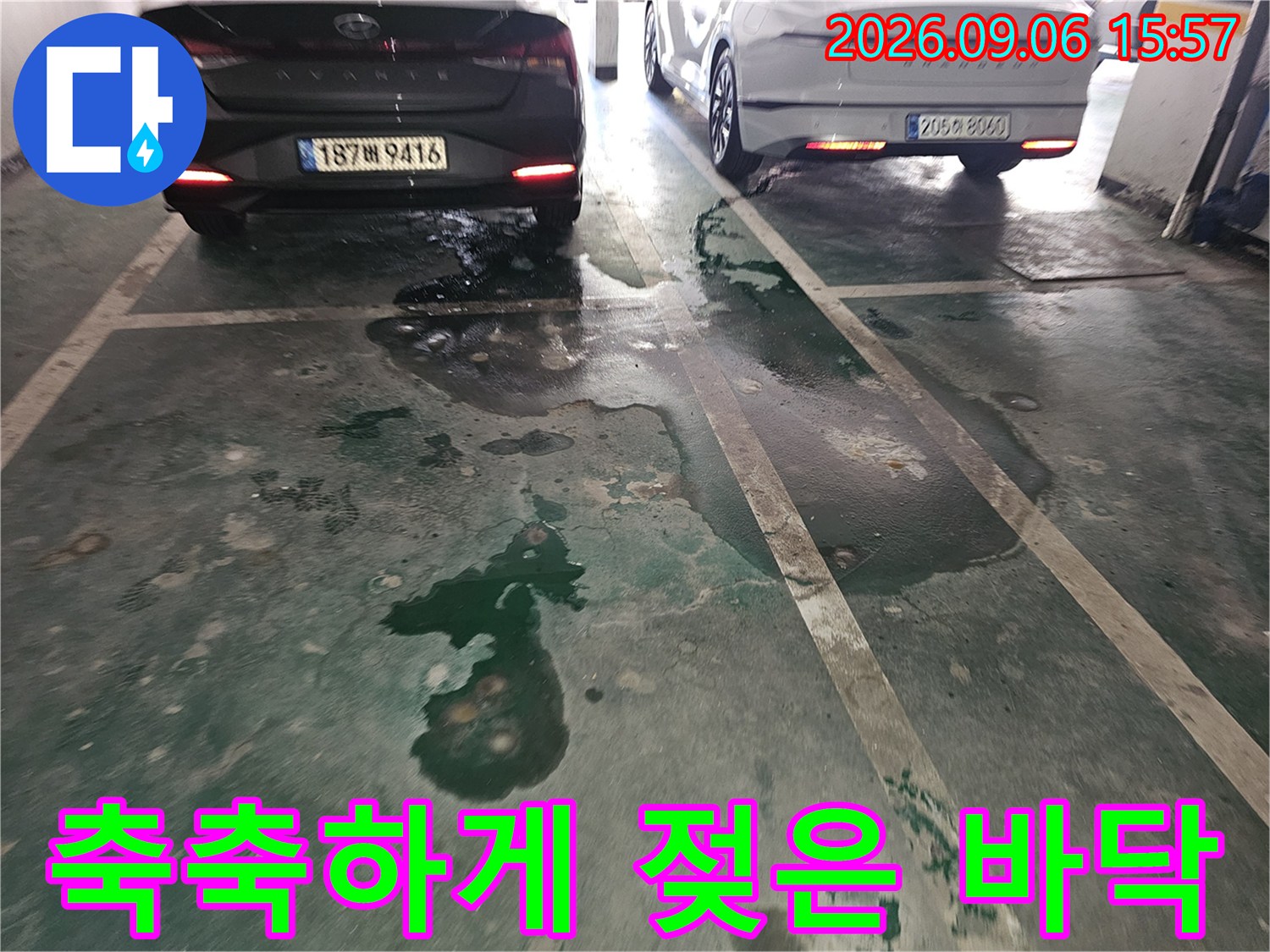 차량 아래쪽 주차장 바닥에 번져 있는 물기 흔적