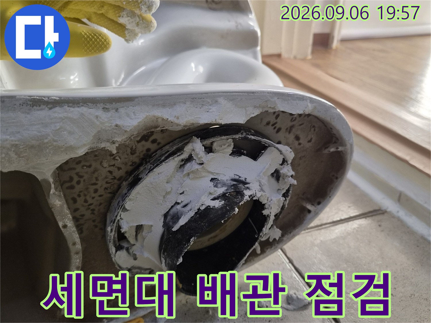 세면대 하단 배수 부속과 타일 사이의 틈새를 근접 촬영한 사진입니다.