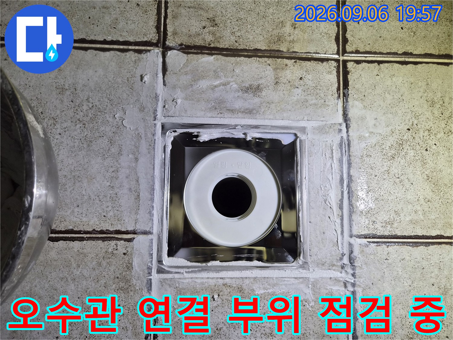 타일 사이로 노출된 하얀색 배관과 주변의 거친 마감 상태를 보여주는 사진