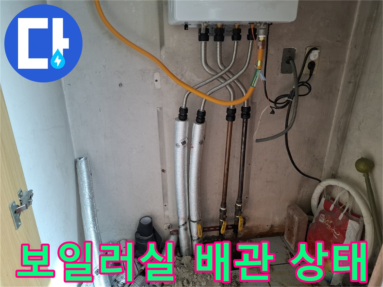 보일러 하단에 연결된 다양한 규격의 급수 및 온수 배관 모습
