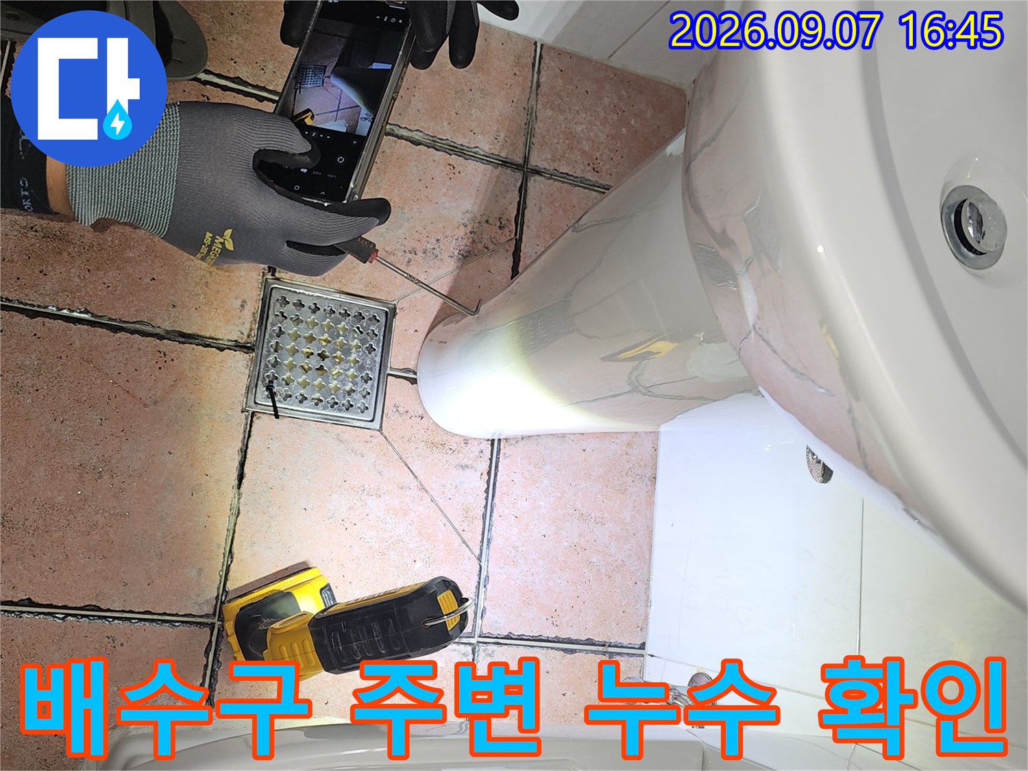 세면대 아래쪽 배수구 유가 부근을 스마트폰으로 촬영하고 있습니다.