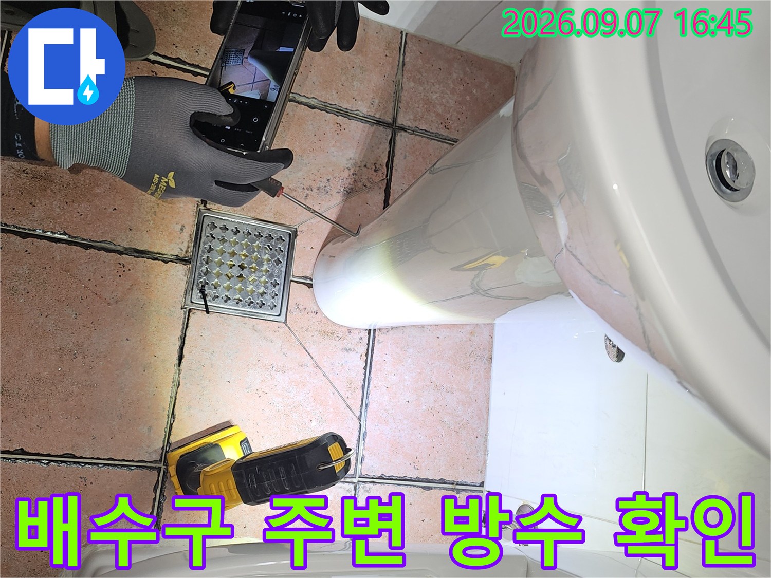 스마트폰과 측정 장비를 활용하여 화장실 바닥 유가 부근의 누수 지점을 정밀하게 촬영하고 있습니다.