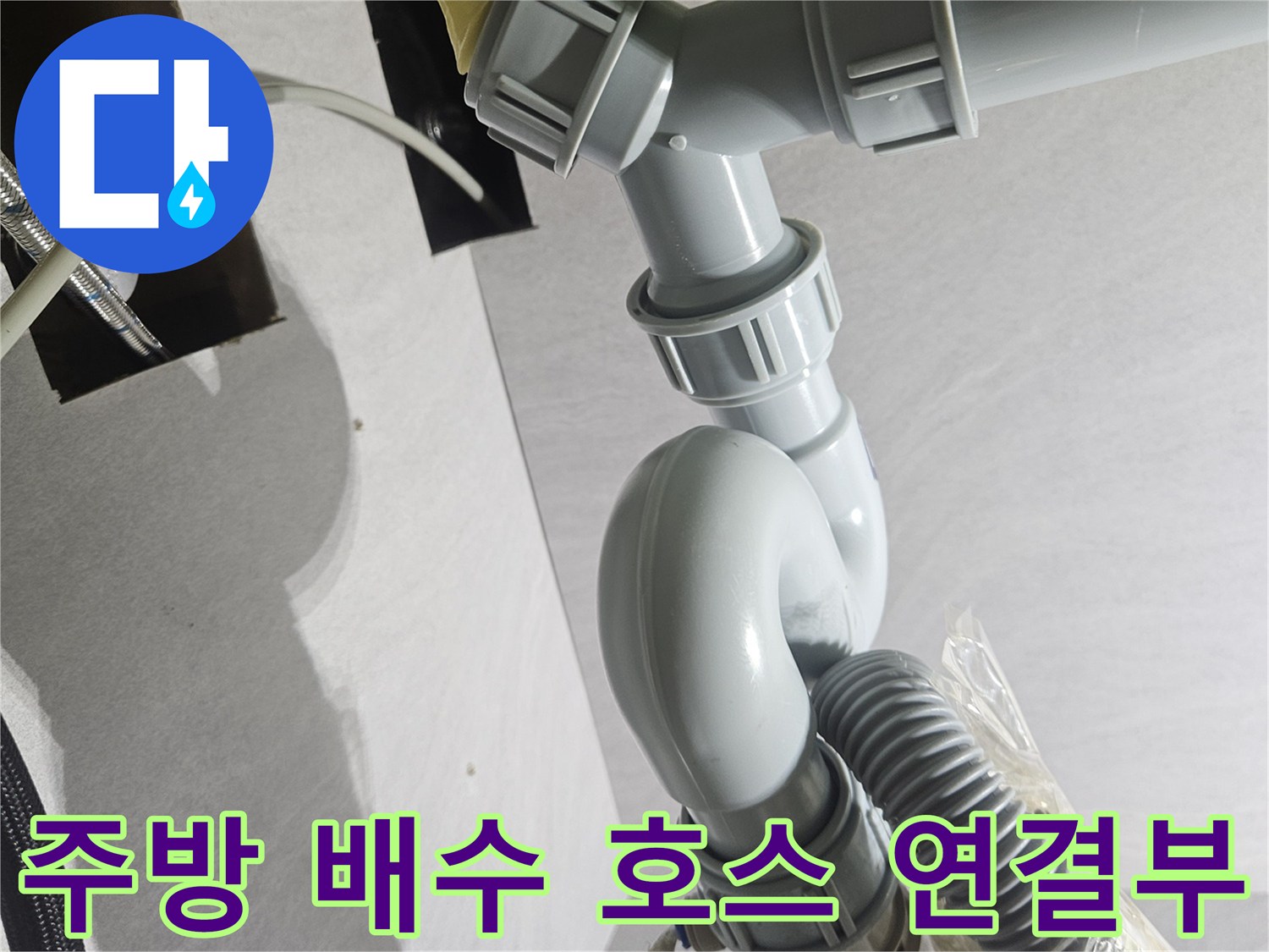 누수 부위를 찾아 재정비한 싱크대 하부의 회색 PVC 배관-결합 상태 확인