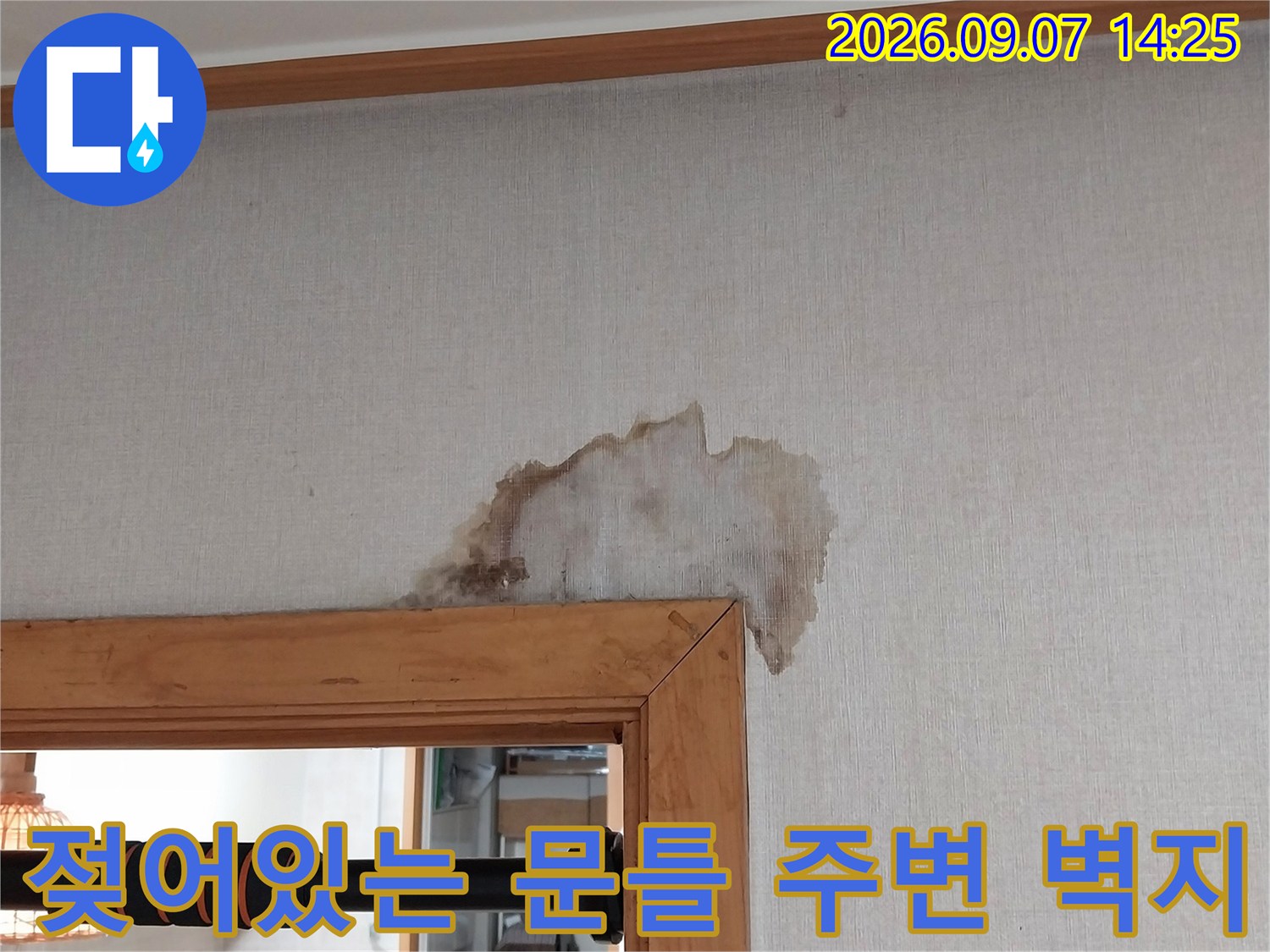 문틀 상단부의 젖은 벽지와 누수 흔적을 나타내는 이미지