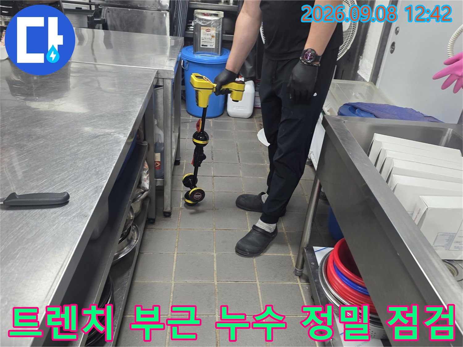 주방 조리대 아래 배수 트렌치 구역에서 누수 여부를 확인하기 위해 장비를 사용하는 모습입니다.