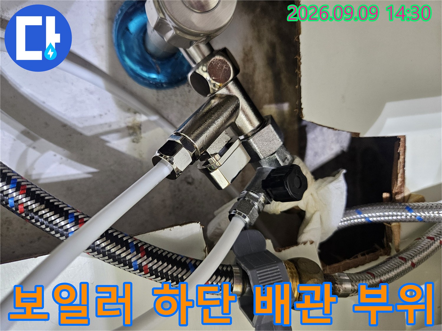 보일러 하단의 금속 밸브와 스테인리스 호스가 연결된 배관 구조입니다.
