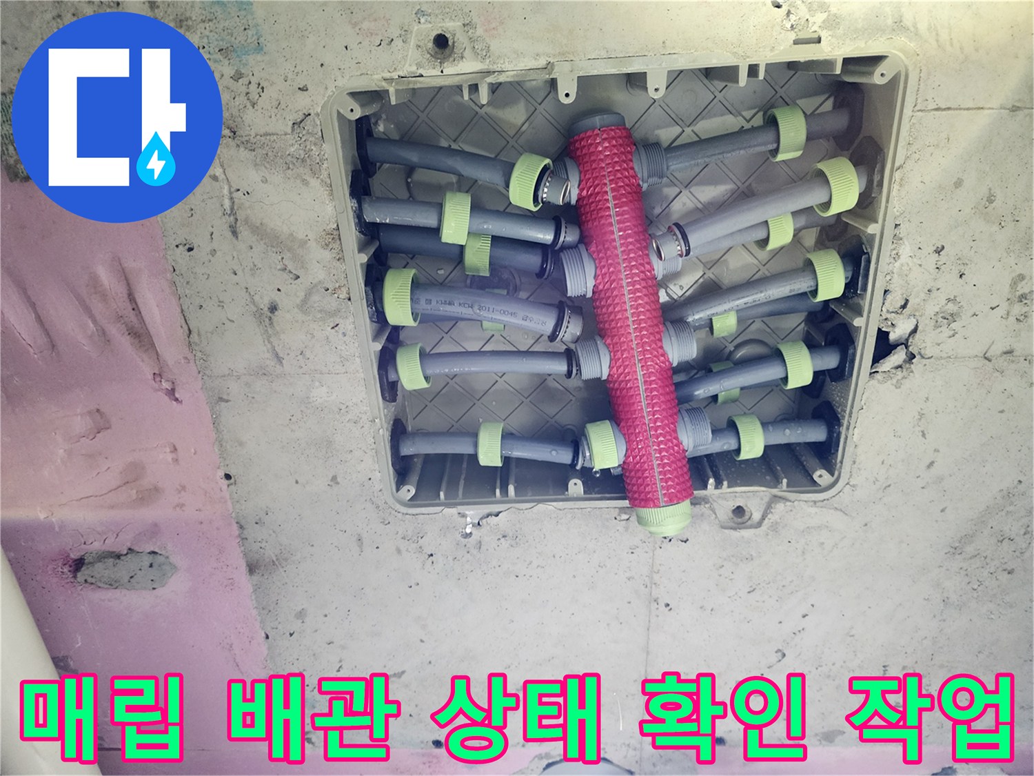 분홍색 보온재와-회색 배관이 얽혀 있는 배관 함 내부