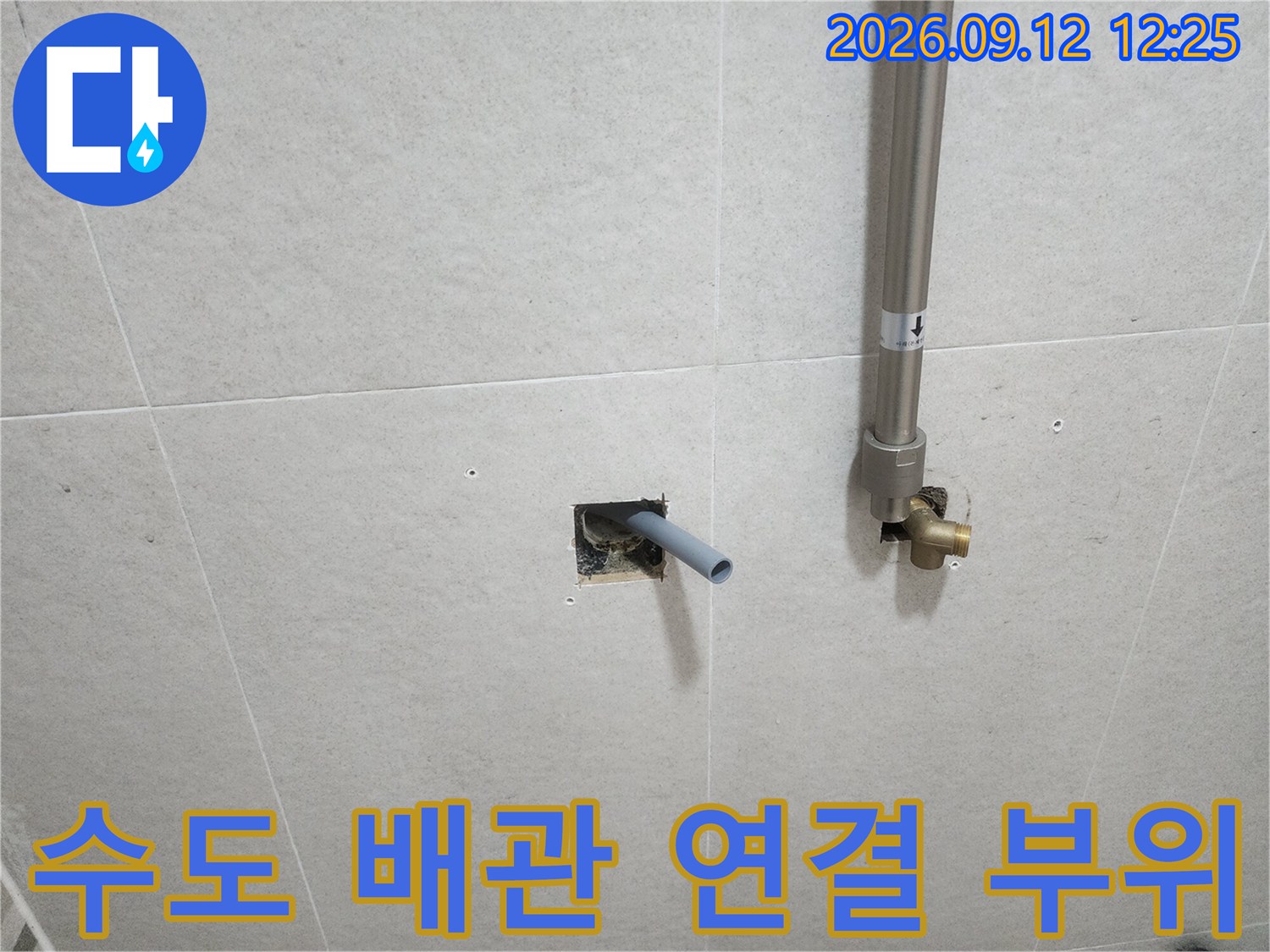 타일 뒤로 드러난-매립형 수도 배관과 금속 연결 부품입니다.