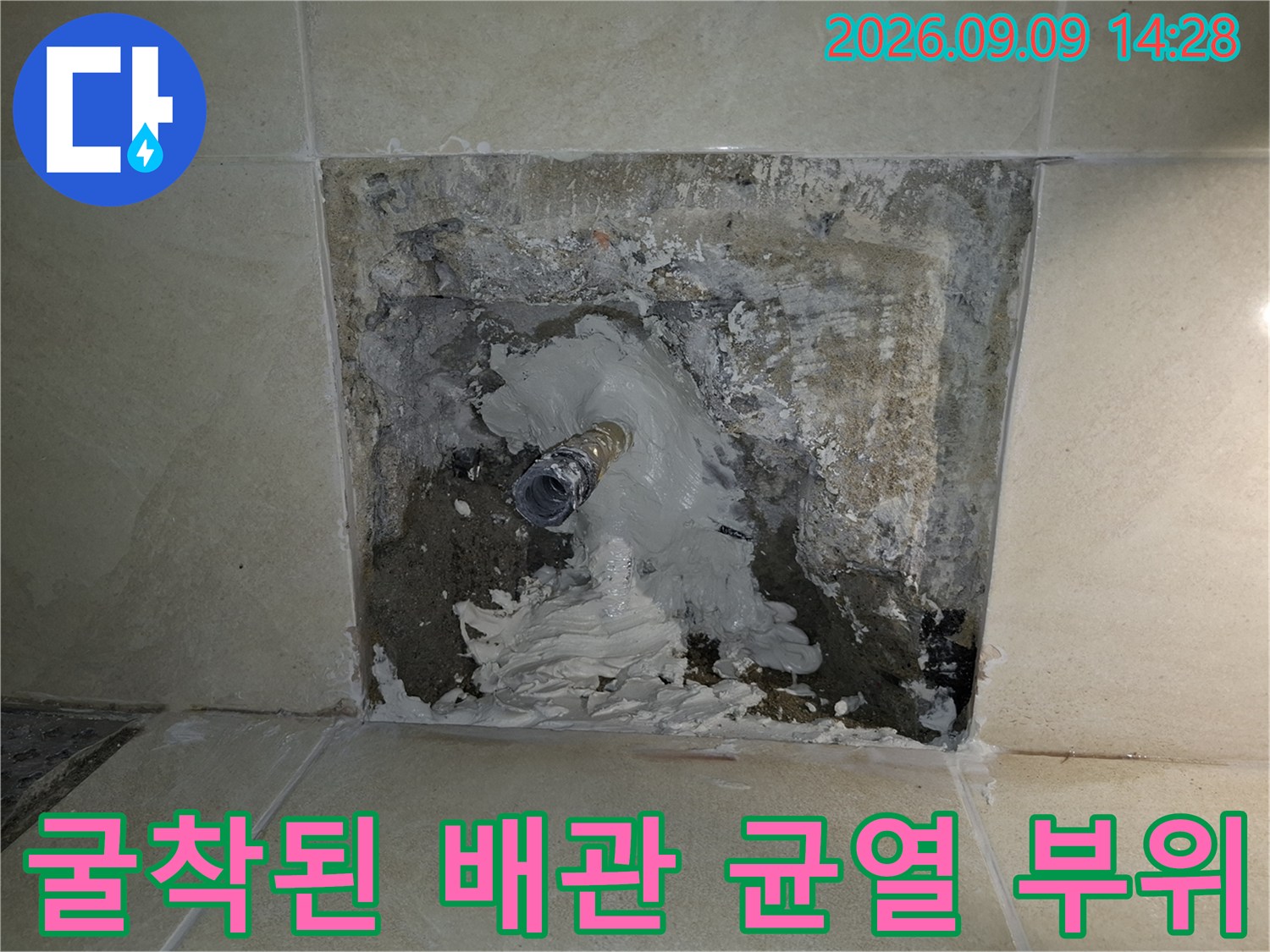 타일 제거 후 드러난 배관의 파손된 틈새를 상세히 보여줍니다.