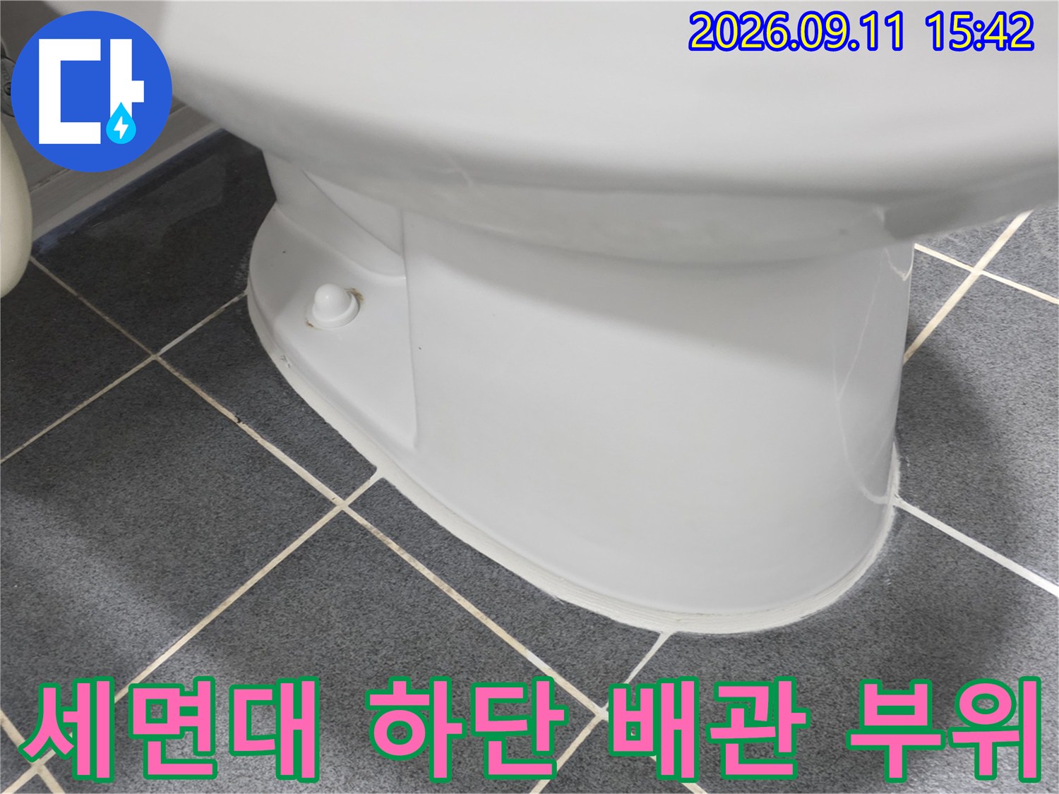 세면대 아래쪽 흰색 도기 부분과 회색 타일 바닥의 접점