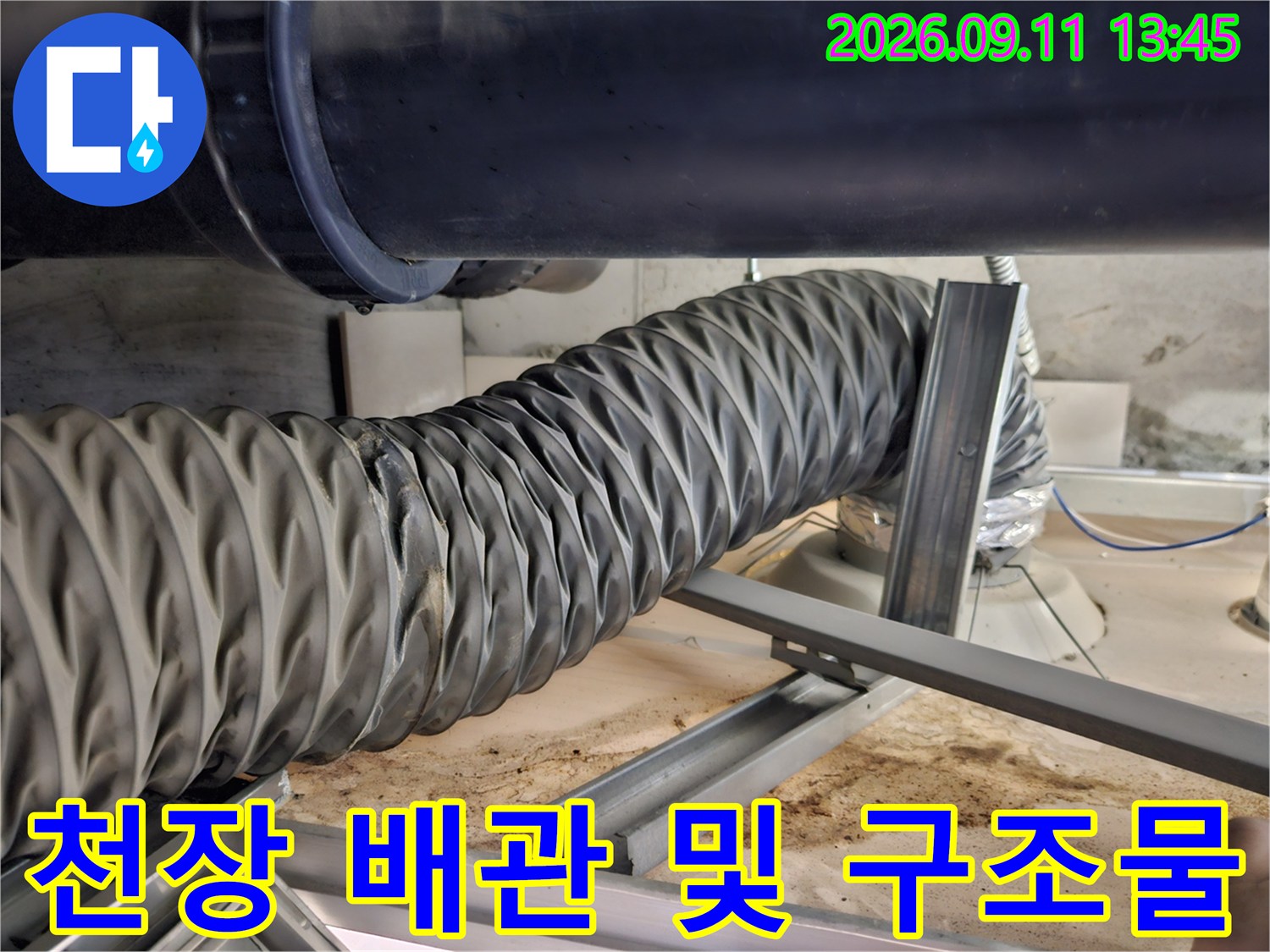 굵은 검정 배관과 주름진 배관이 교차하는 천장 내부 모습입니다.
