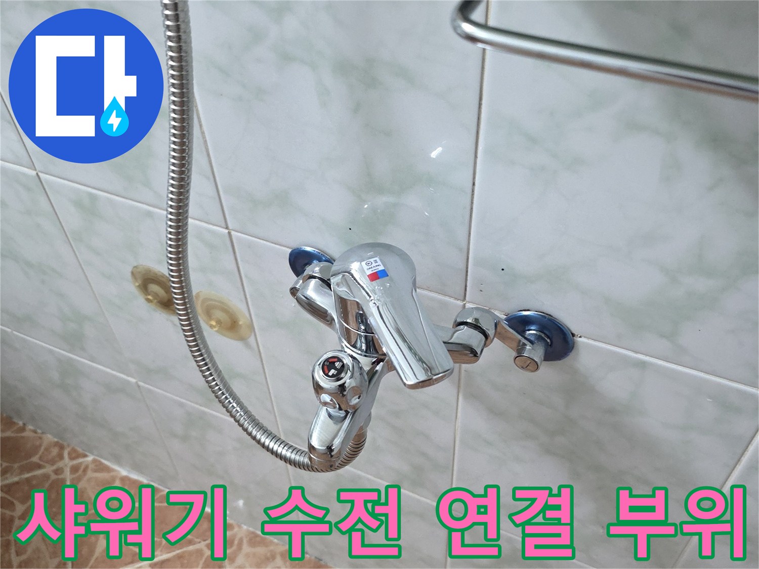 벽면 타일에 설치된 샤워 수전과 은색 샤워 호스 상세 모습