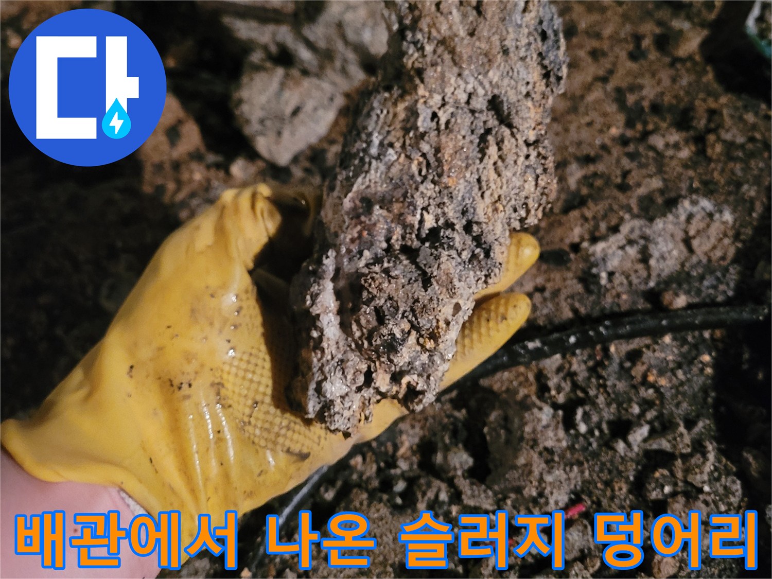 노란 장갑으로 들고 있는 커다란 배관 슬러지 덩어리