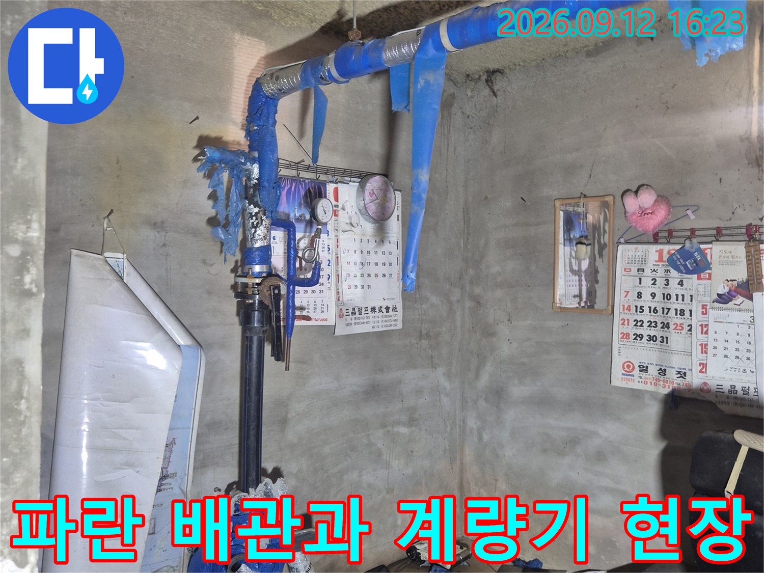 천안 서북구 아파트 지하 공간의 파란색 보온재가 감겨진 급수 배관과 계량기 모습
