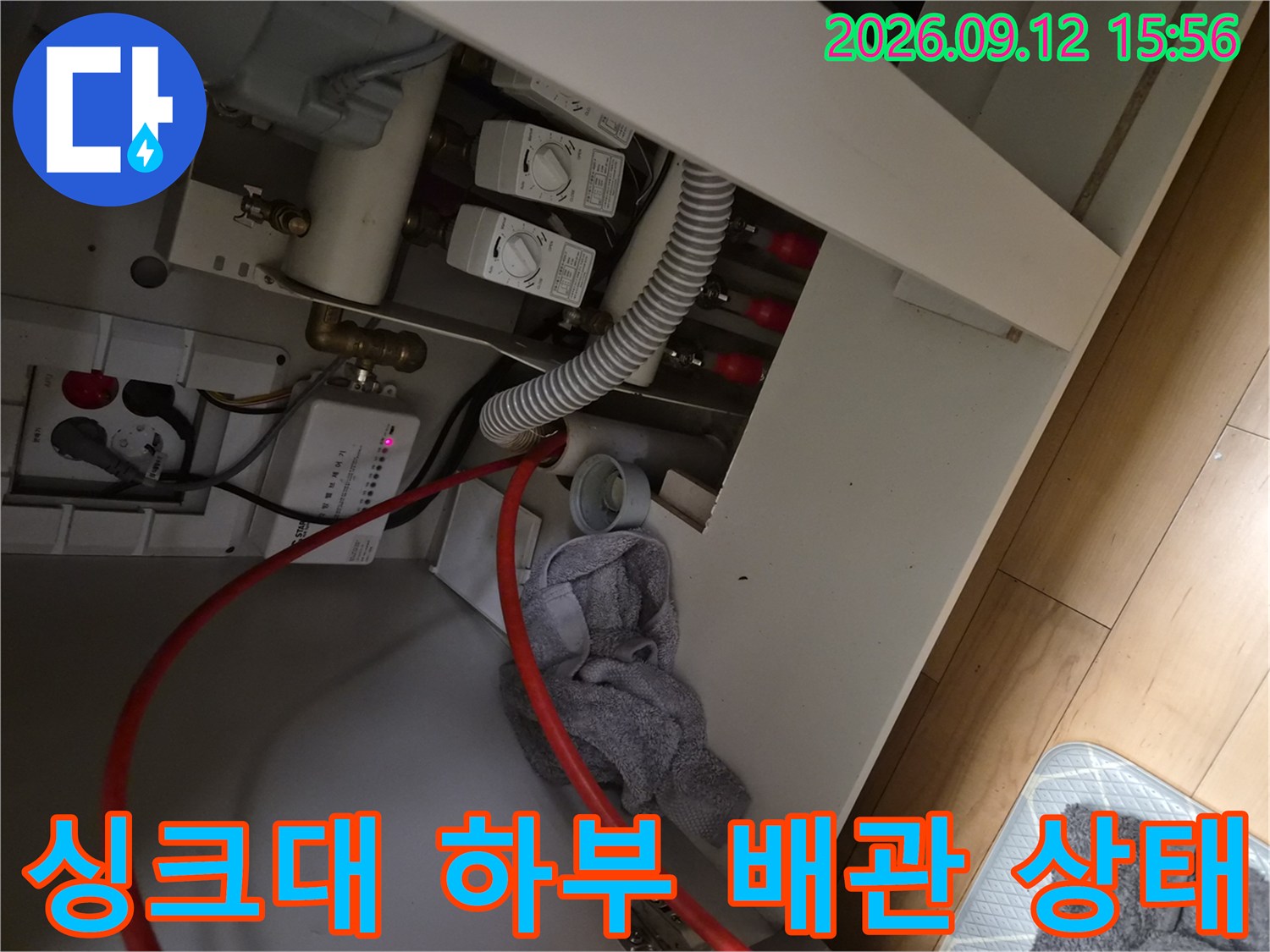 싱크대 하부장 내부의 급수 밸브와 배수 호스 연결 모습