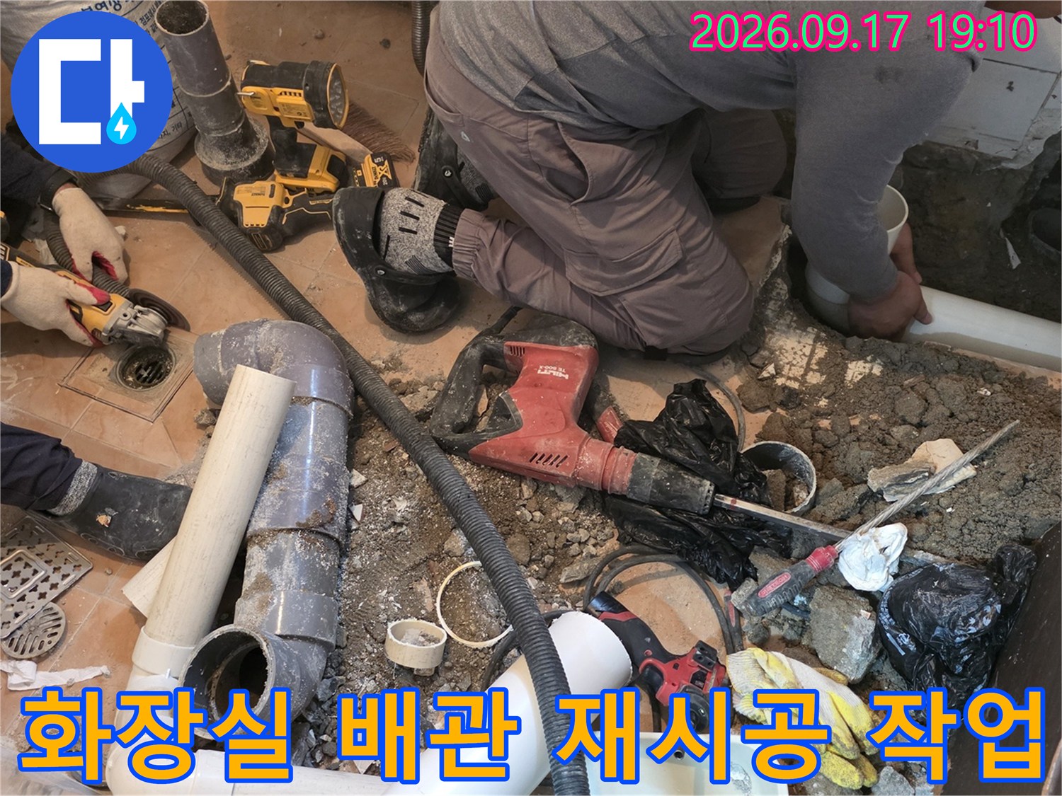 굴착된 화장실 바닥에 배치된 새로운 PVC 배관과 수리용 공구입니다.