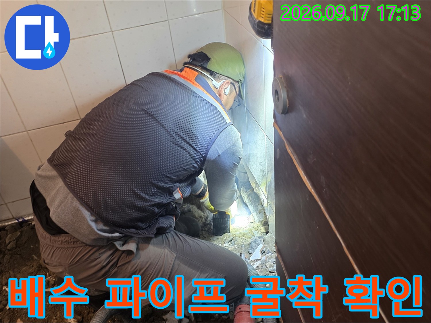굴착된 화장실 바닥에서 배수 파이프를 점검하는 전문 엔지니어의 모습입니다.