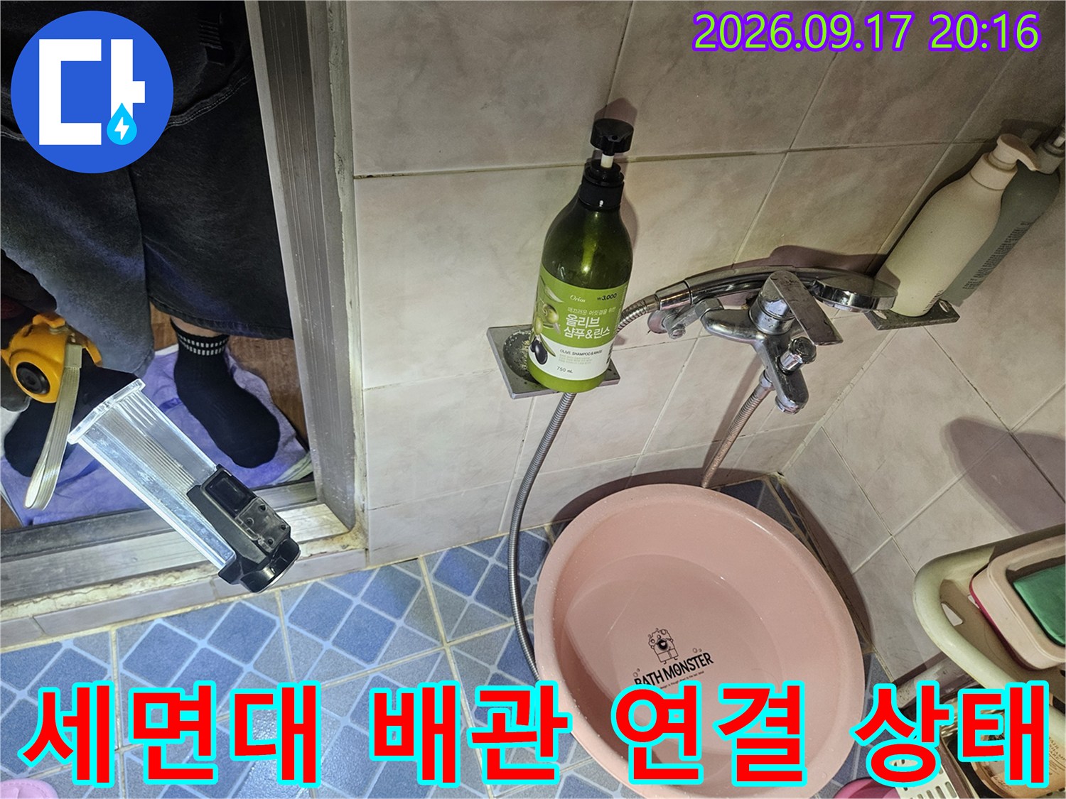 세면대 하단 수전 부속과 은색 배관이 연결된 모습입니다.